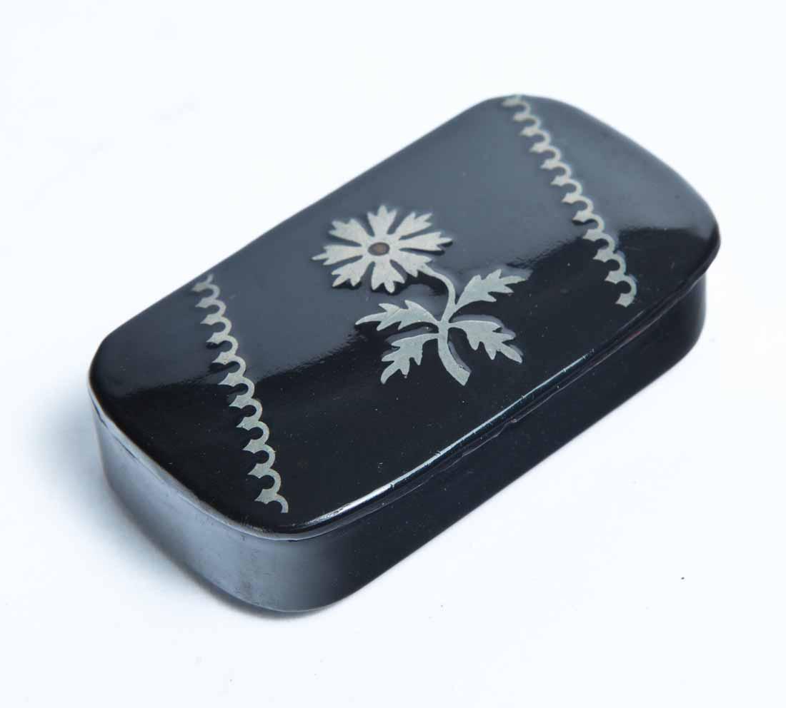 LACQUERWARE SNUFF BOX: Rectangular with curved corners and inlaid pewter decoration of a flower and geometric accents. .5"h. 2.75"l. 1.5"d.