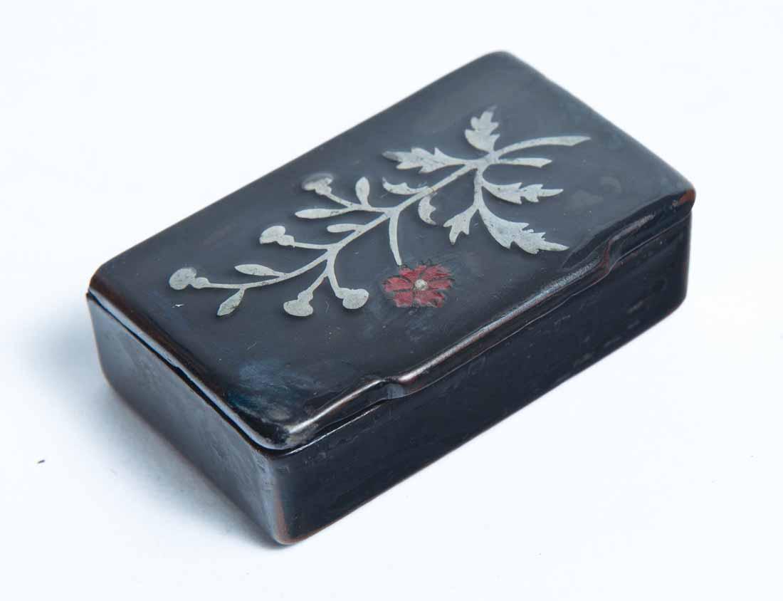 LACQUERWARE SNUFF BOX: Rectangular with inlaid pewter floral decoration, one flower with red enamel decoration. .5"h. 2.25"w. 1.5"d.