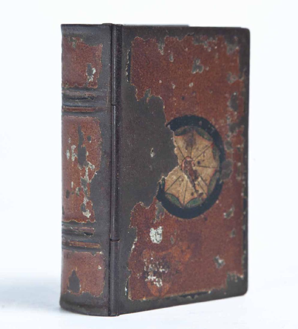 BOOK SNUFF BOX: Tin with red, white and black paint decoration. Purchased from Garth's Auctions, Delaware, Ohio. .75"h. 2.75"w. 1.75"d.