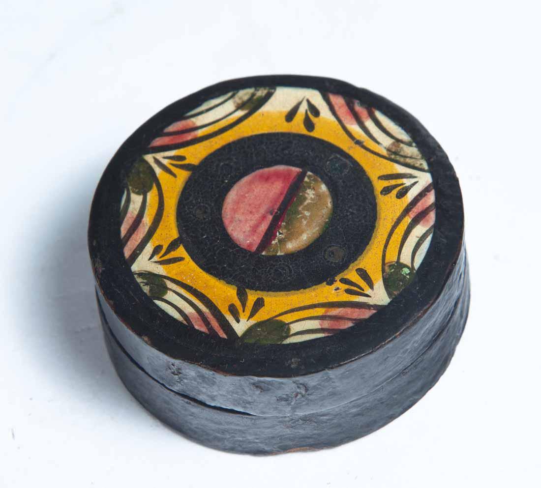 PAINT-DECORATED LACQUERWARE SNUFF BOX: Round with yellow, red, black and white decoration. Purchased from Garth's Auctions, Delaware, Ohio. "h. 1" dia.