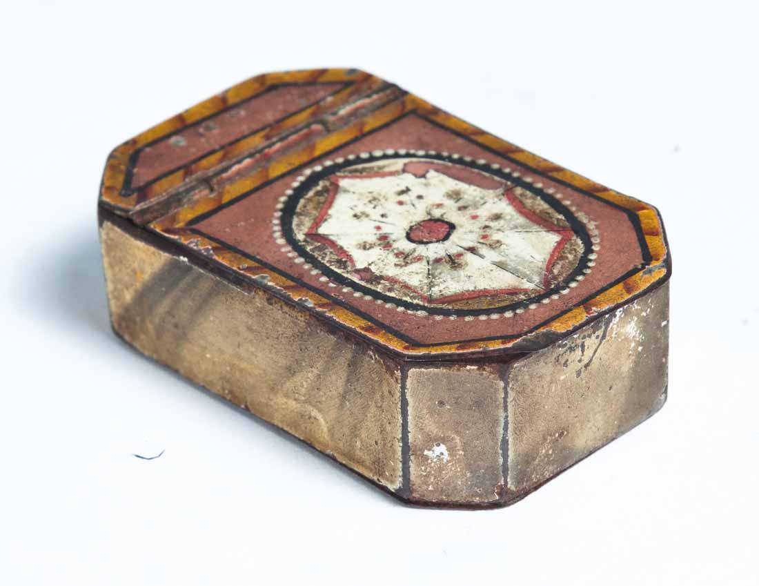 DECORATED TOLE SNUFF BOX: Rectangular with cut corners and hinged lid. Paint decoration consists of orange, red, salmon, white and black geometric designs on lid and yellow and black on sides and base. Purchased from Garth's A