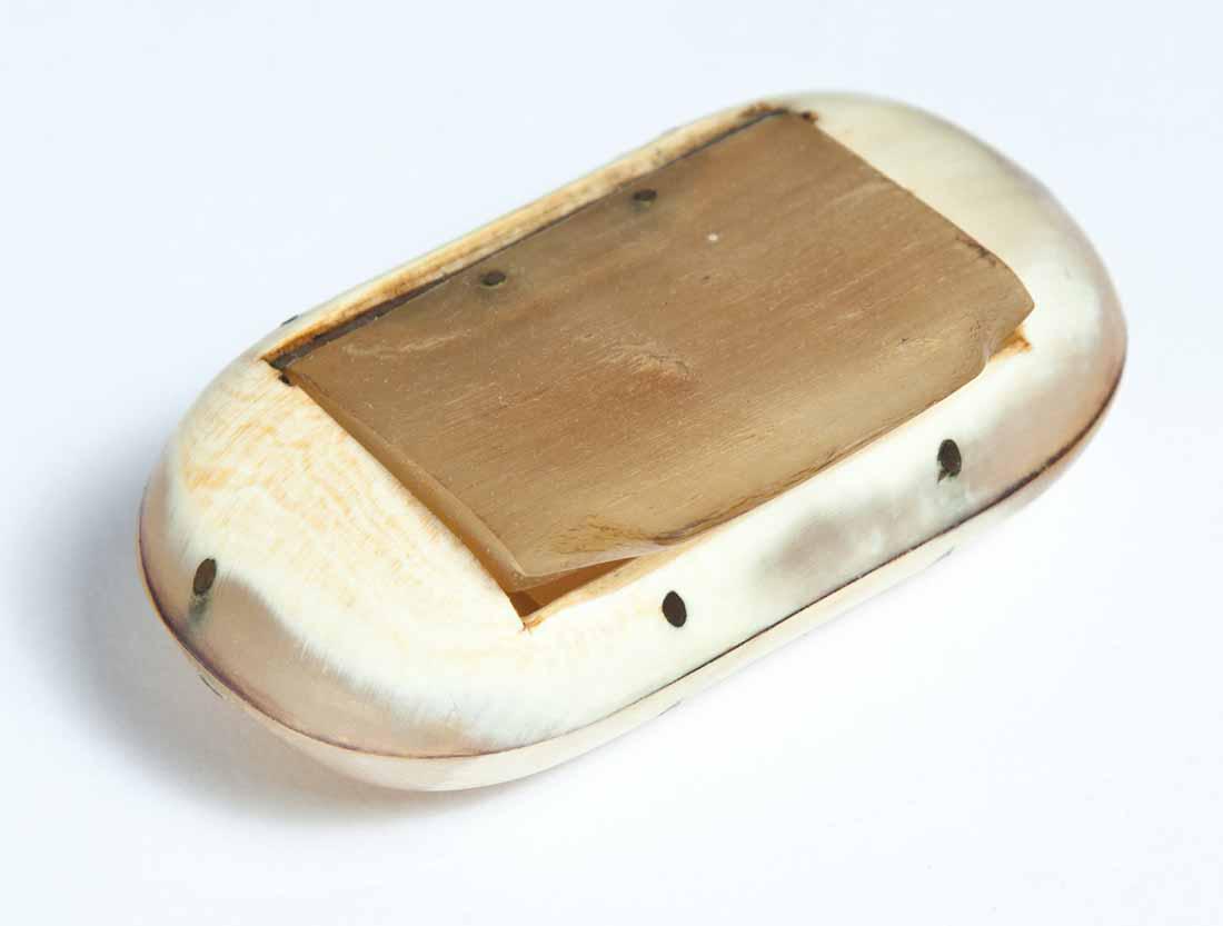 CARVED HORN SNUFF BOX: Oval with nailed construction and hinged lid. .5"h. 2.75"w. 1.5"d.