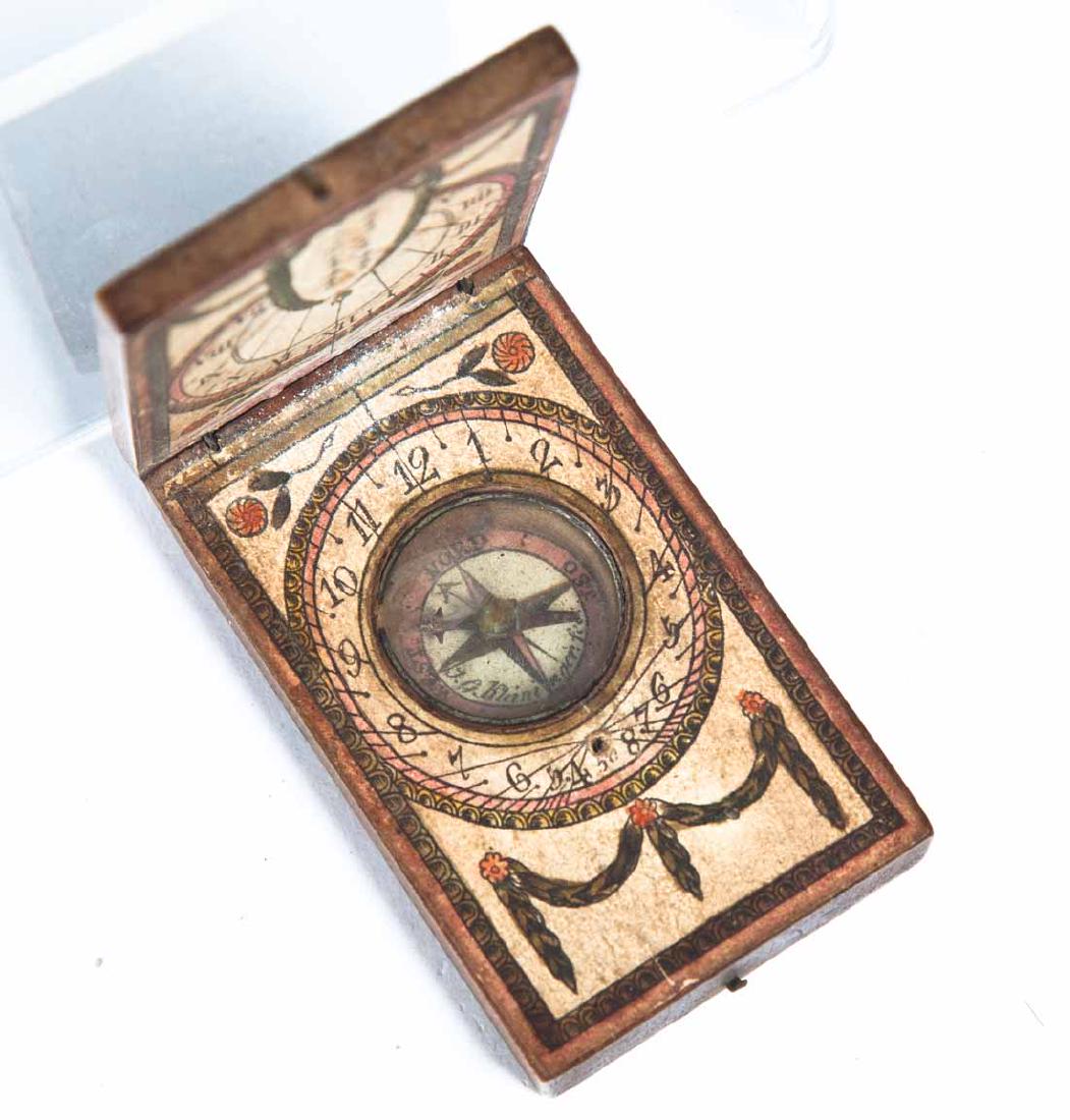 KLEININGER DIPTYCH SUNDIAL COMPASS: C. 1785. Wooden case with handcolored paper on the interior with times in Arabic and Roman numerals and floral and swag accents. The exterior of the lid contains listings of European and American citi