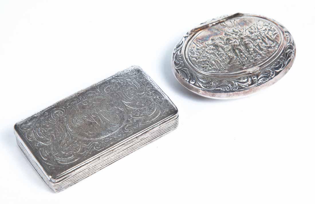 TWO SNUFF BOXES: Rectangular metal box with engraved scrollwork and monogramm. Unidentified hallmark. .5"h. 2.75"w. 1.5"d. Oval box with embossed scrollowork and conquistadors. .5"h. 2.5"w. 2"d.