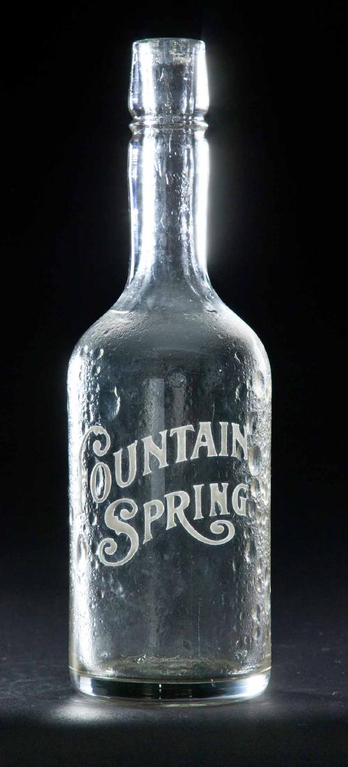 ENAMELED LABEL BAR BOTTLE: Colorless pre-Prohibition bottle with bubbly texture and "Fountain Spring" advertising. 11.25"h.