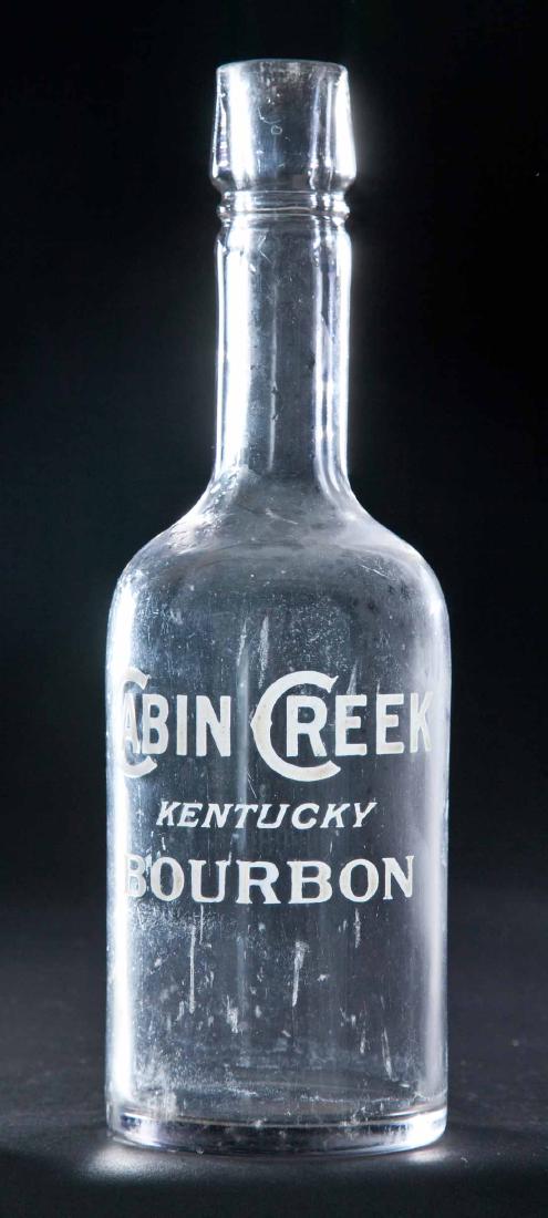 ENAMELED LABEL BOURBON BOTTLE: Colorless pre-Prohibition bottle with label for "Cabin Creek Kentucky Bourbon". 11"h.