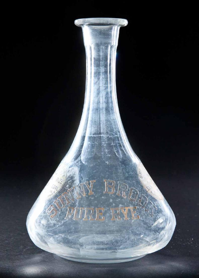 ENAMELED LABEL RYE BOTTLE: Colorless pre-Prohibition decanter with flared body and paneled neck and "Sunny Brook Pure Rye" label. 9"h