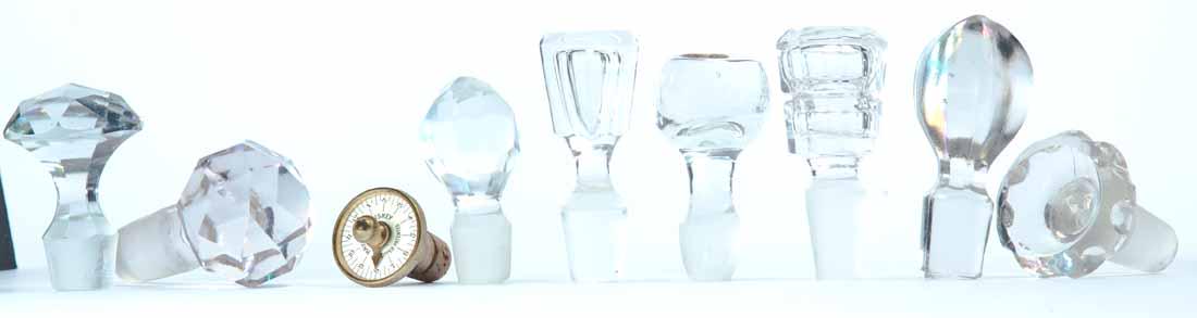 GROUP OF STOPPERS: Nine (9) stoppers including three (3) faceted ball stoppers, one air-trap ball stopper, four (4) other clear and one brass with "Hayer Whiskey" advertising and clock face. 2"-3"l.