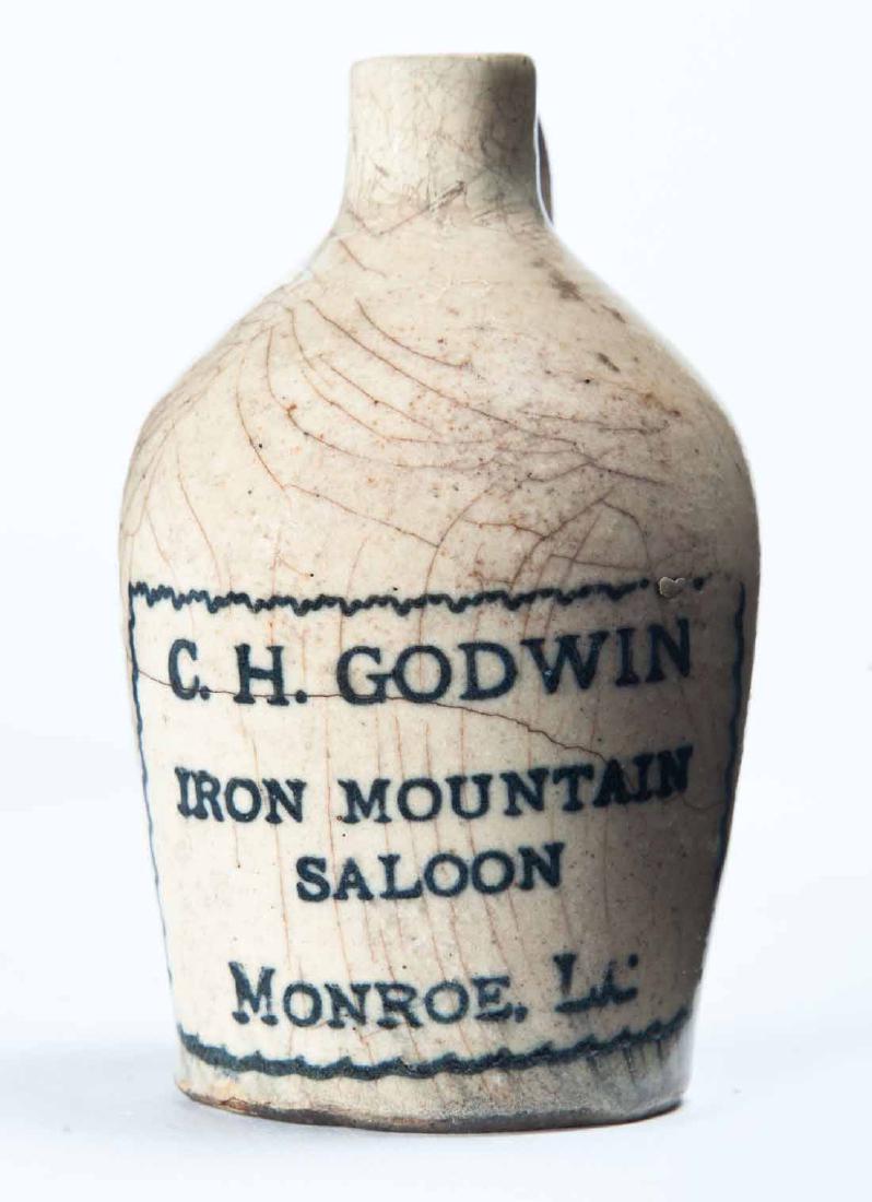 MONROE, LOUSIANA MINIATURE ADVERTISING JUG: Cream glaze and stamped advertisement "C.H. GODWIN IRON MOUNTAIN SALOONâ€¦" 3.25" high.