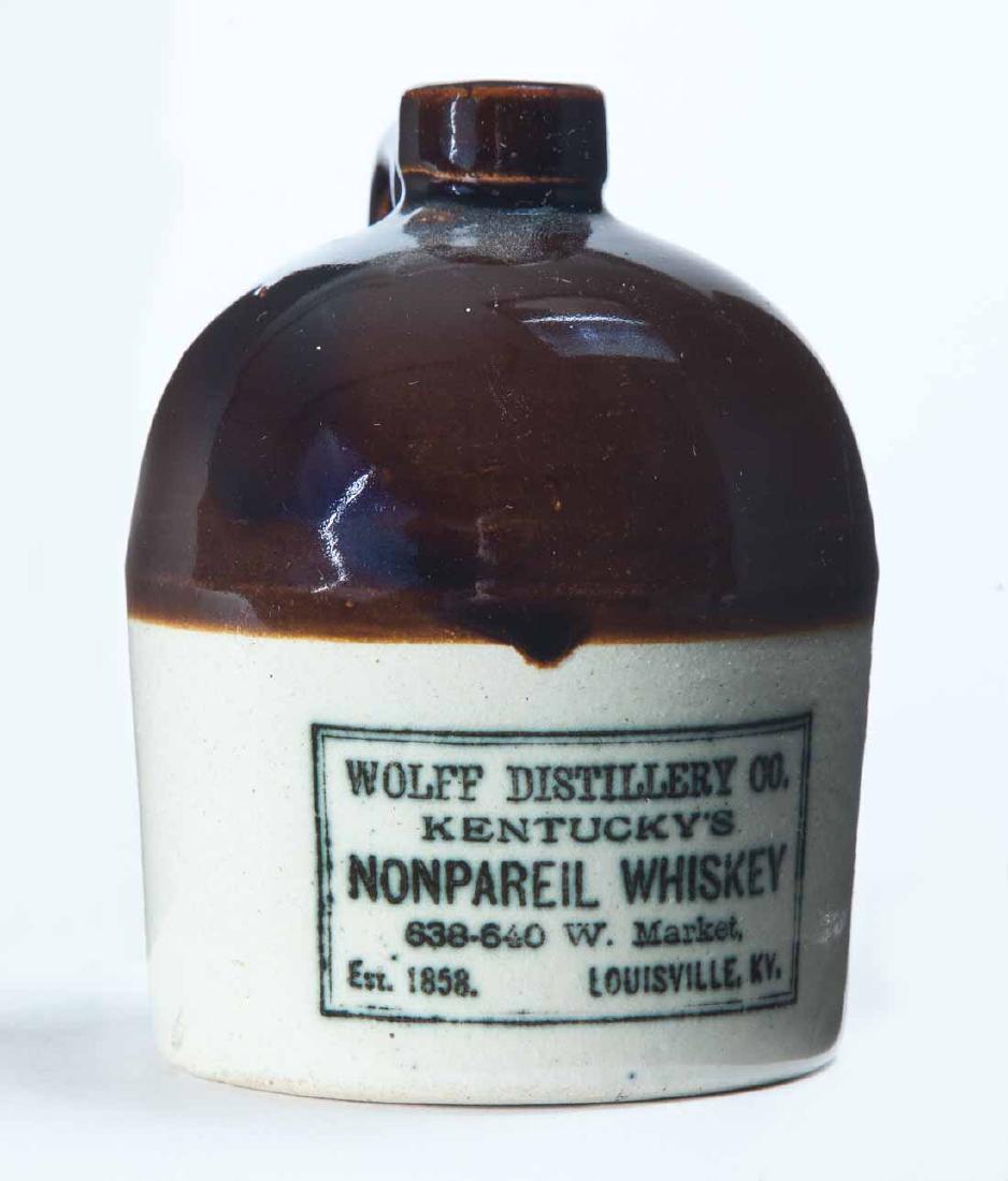 LOUISVILLE, KENTUCKY MINIATURE ADVERTISING JUG: Bicolor glaze and stamped advertisement "WOLFF DISTILLERY CO. KENTUCKY'S NONPAREIL WHISKEYâ€¦" 4.25" high.