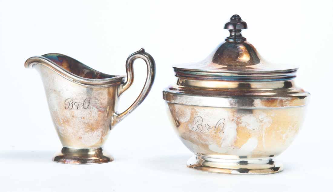 B&O RAILROAD SILVERPLATE CREAM AND COVERED SUGAR: Pitcher with flared foot and scrolled handle. Sugar with flared foot and lid. Both with engraved "B&O" on front and made by "R. Wallace". 3.25"h. 4"h.