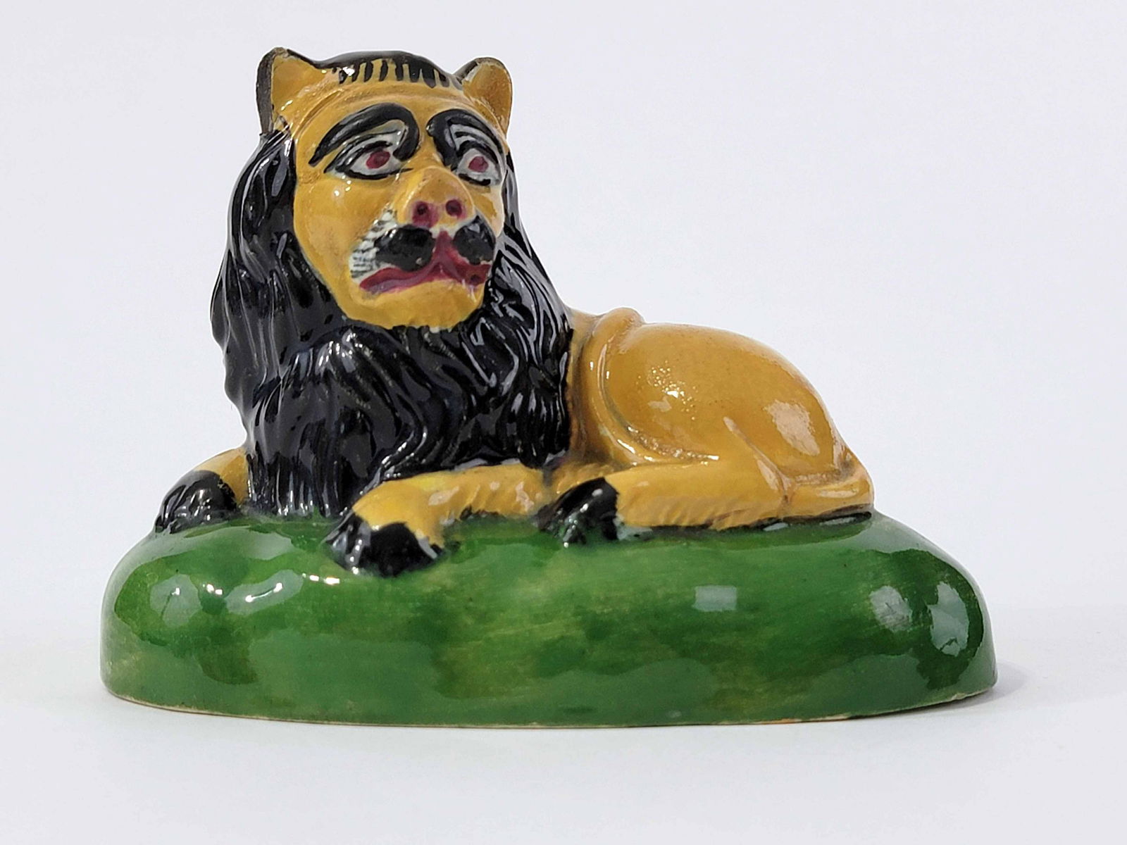 UNUSUAL SIGNED PEARLWARE LION: English, early 19th century. Thickly molded recumbent lion, colorfully glazed, and with incised signature "John Smith" on the underside. 4.5" long. (LR104)