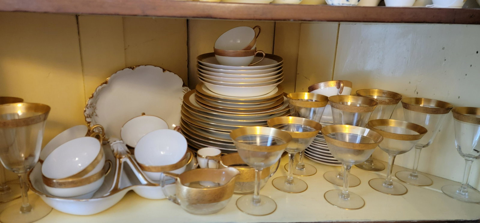 SET OF GOLD RIMMED CHINA AND GLASS: American/European, 20th century. "Hutschenruther Selb Bavaria" china with dinner plates, bowls, salad plates, cups and saucers, sauce dishes, platters, etc. Also included are miscellaneous gold-rimmed