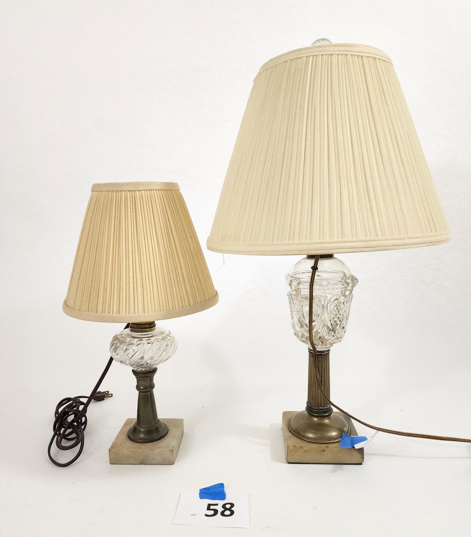 TWO OIL LAMPS: American, 19th century. Two assembled glass whale oil lamps on square marble bases converted to electricity. Bedside accent lamp is 15" high, larger table lamp with crystal finial is 21" high.