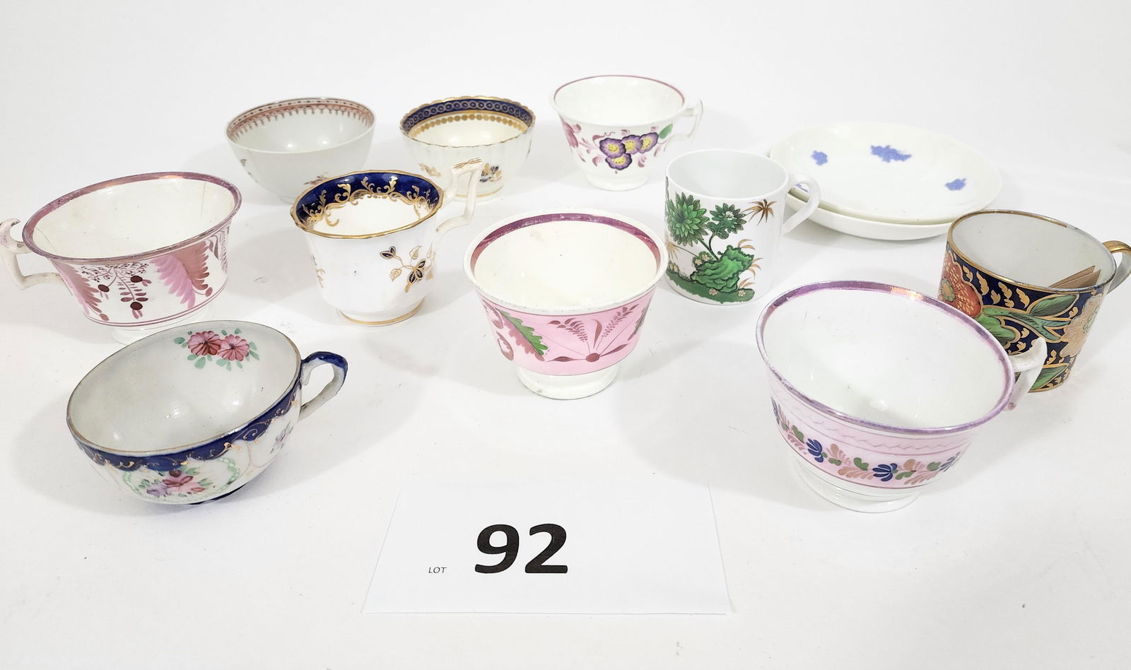 COLLECTION OF ENGLISH CUPS AND SAUCERS: 19th century. 3 pink luster cups with and without handles, 2 Chelsea saucers, possible Chinese export porcelain tea bowl, a blue and gilded tea bowl possibily by Worcester, a blue and gold cup c. 1835