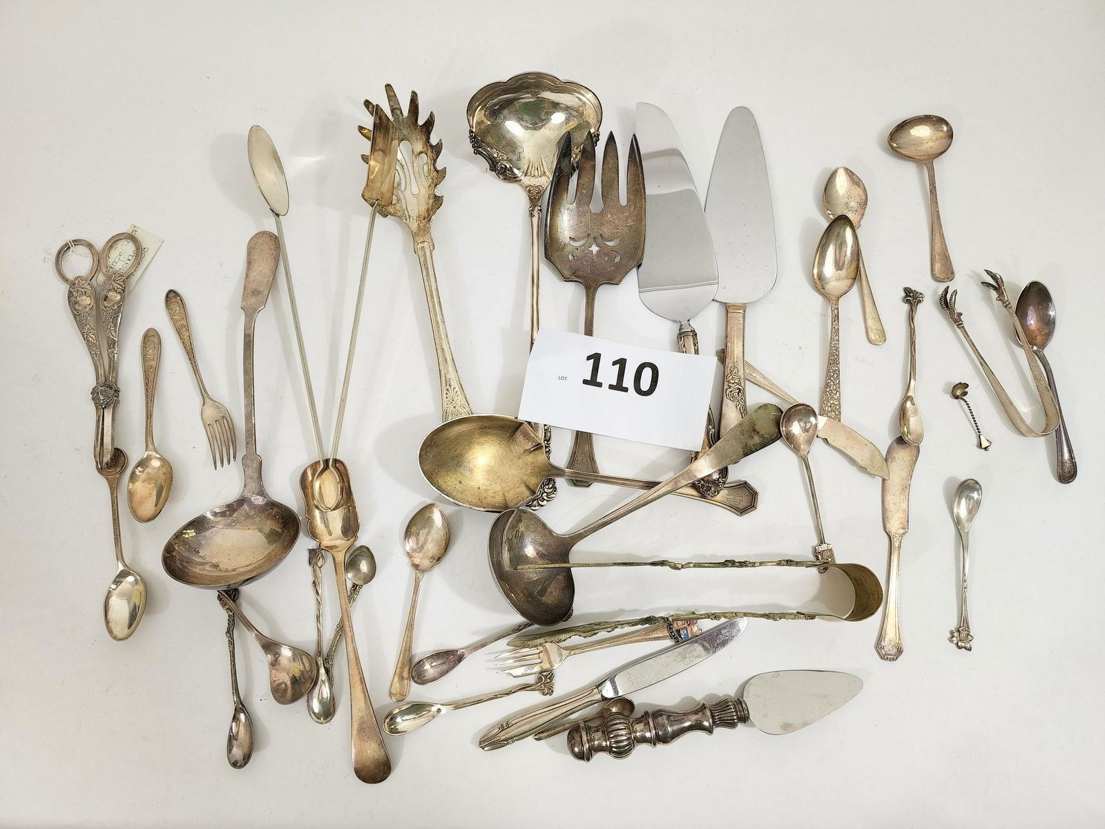 COLLECTION OF SILVER-PLATED UTENSILS: American and British silverplate, mainly E.P.N.S., early 20th century, including serving utensils and souvenir spoons and a beautiful pair of Victorian grape scissors, and Queen Elizabeth II coronatio
