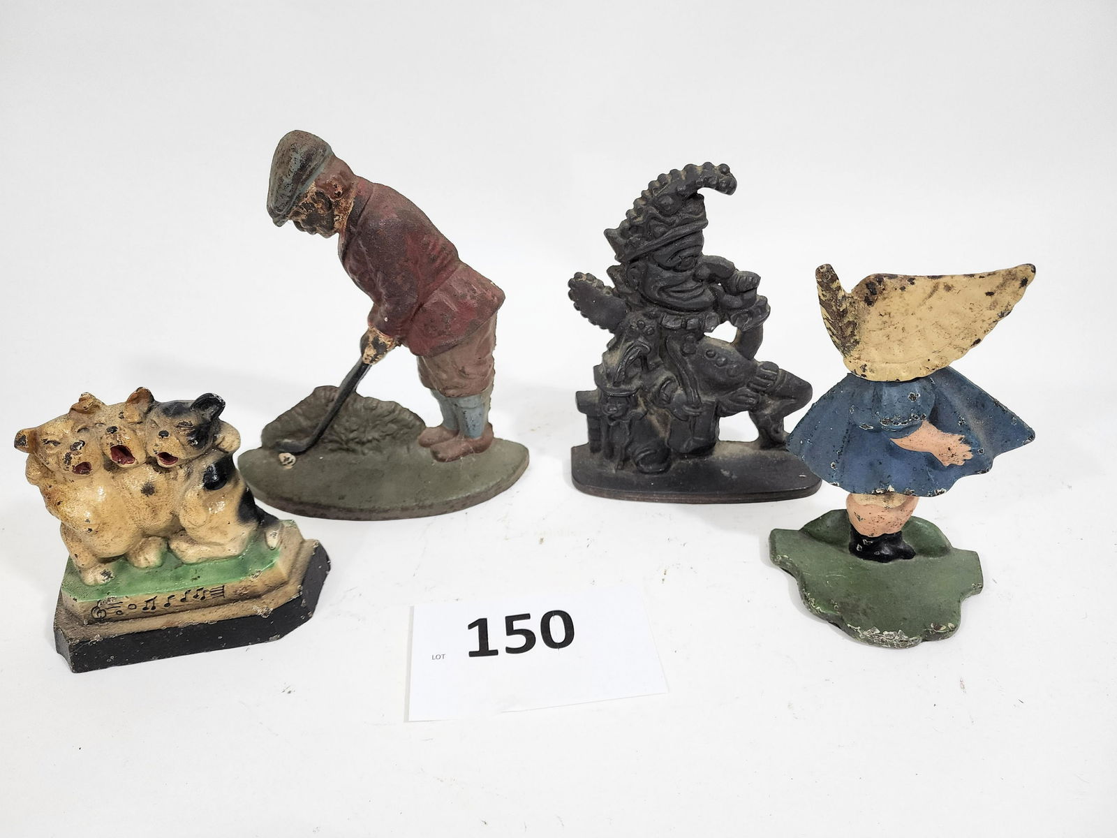 FOUR DOORSTOPS: Late 19th-early 20th century. Includes dogs, a bonnet girl, a golfer, and Punch, 4.5" to 7" high.