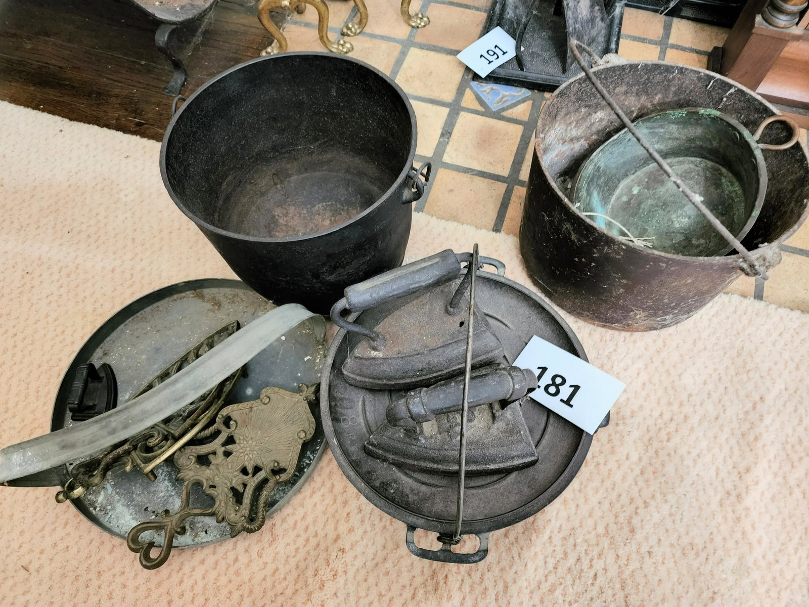 COLLECTION OF KITCHEN IRON: American, late 19th-early 20th century. Includes three cast iron pots, two sad irons, a miniature sad iron, three brass trivets, a tin hanging pan, and a copper pan. Largest pot is 8.75" high.