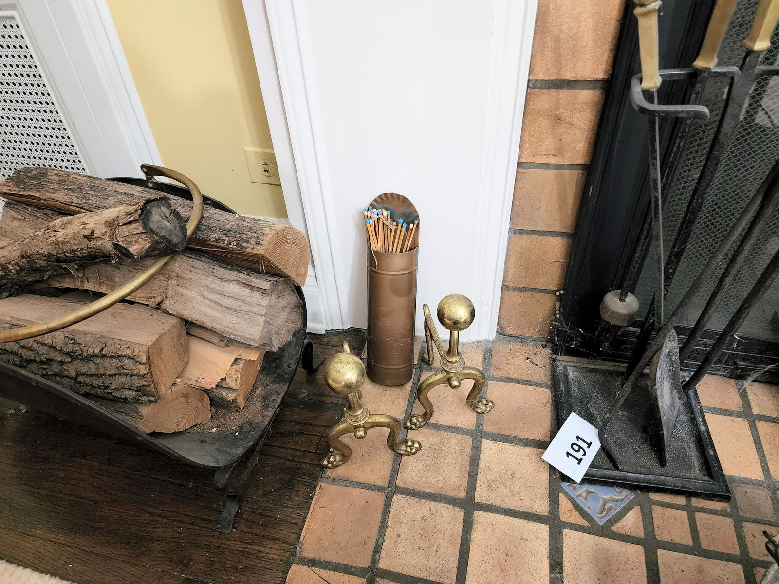 COLLECTION OF FIREPLACE EQUIPMENT: 20th century. Includes a pair of small brass andirons, a set of fireplace tools with stand, a match holder, and a firewood carrier. Tool stand is 22" high.
