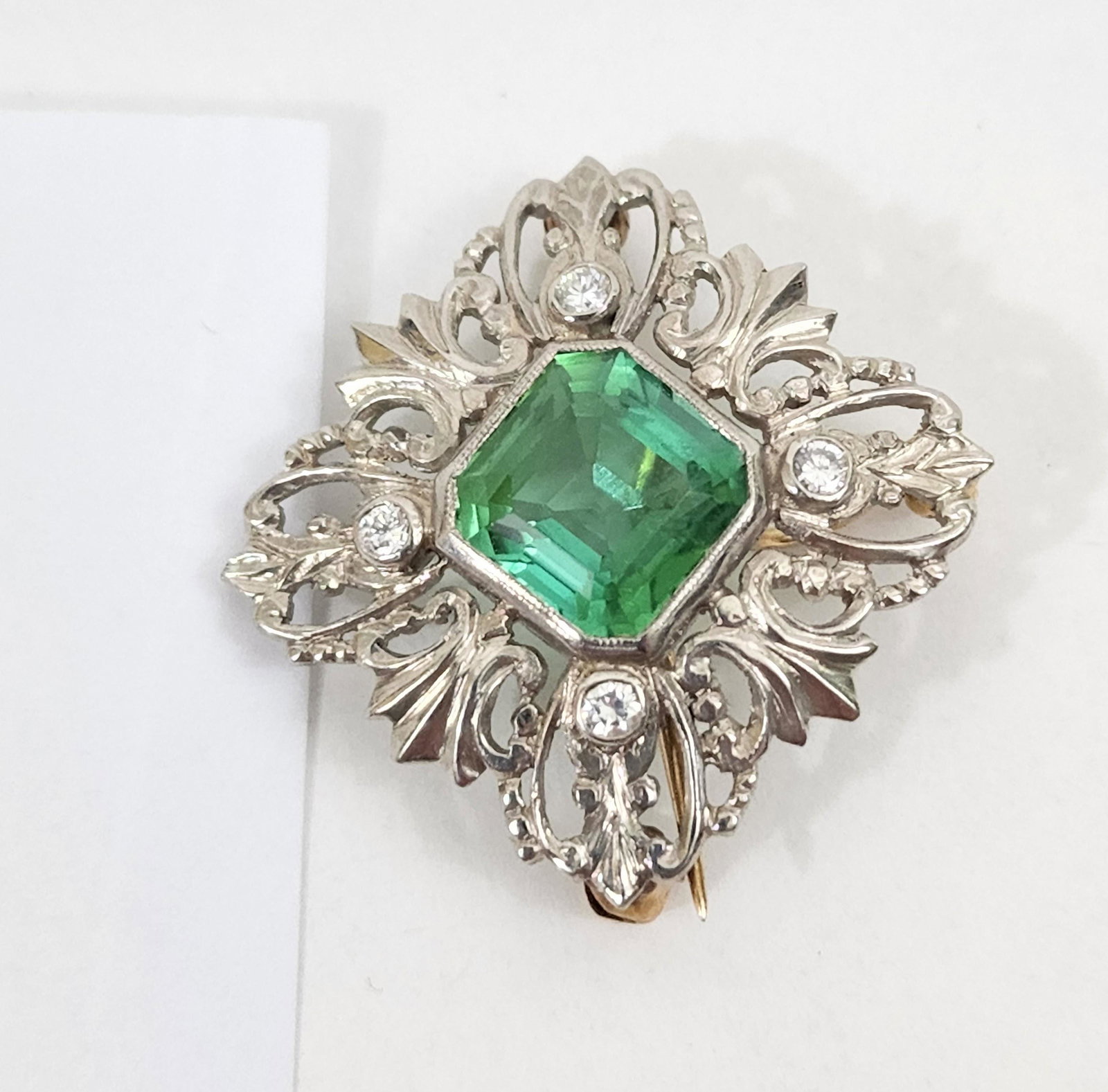 WWII PALLADIUM and DIAMOND BROOCH/PENDANT: American, c. 1939-45 Vintage Palladium diamond and green stone brooch and pendant in diamond shape with four bezel set diamonds and yellow gold pin and loop. Approx. 3g.