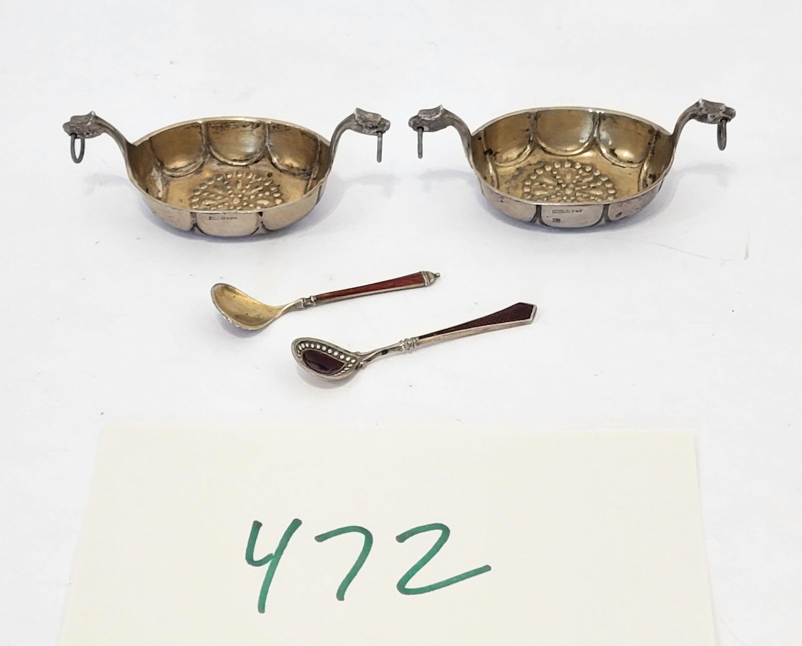 PAIR OF NORWEGIAN SILVER SALT CELLARS: Marked, in the form of Viking ships, with repousse decoration, and with mismatched silver and enamel salt spoons. Cellars are 3" long, total weight is 38g.