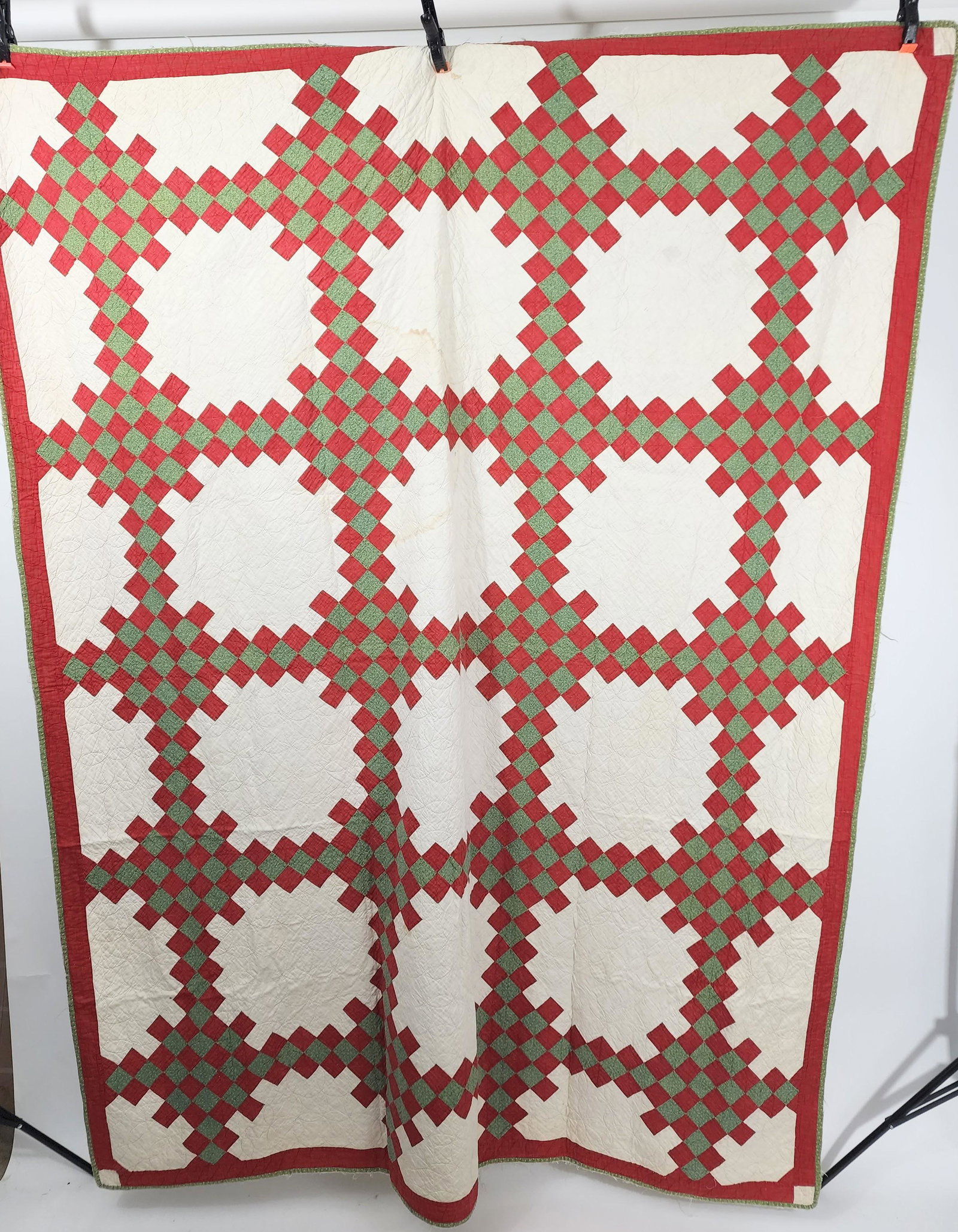 AMERICAN PIECED QUILT: Early 20th century. Triple Irish Chain quilt, with pieced red and green fabric on white ground. Circular pumpkin seed Amish-style quilting. Approx. 82" x 65".