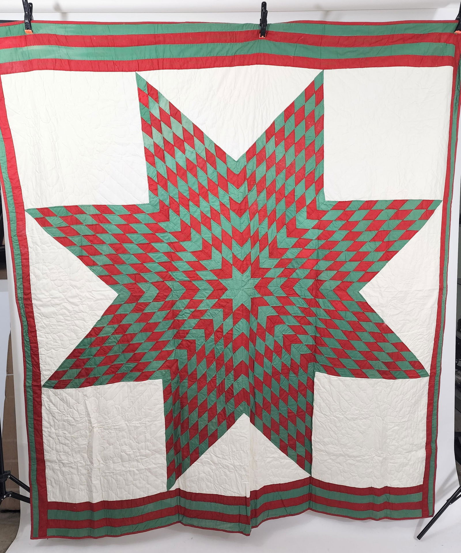 AMERICAN LONE STAR QUILT: Mid-20th century. Lone Star quilt, pieced in red and green on white ground. Border is red and green bands, with an extra band on one side. Approx. 82" x 72".