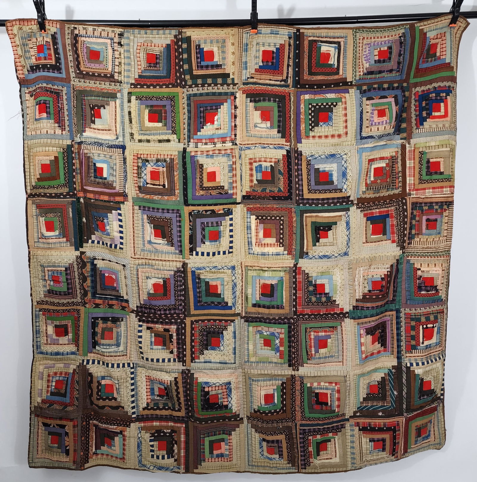 AMERICAN LOG CABIN QUILT: Late 19th century. Sunshine and Shadows set, Log Cabin quilt with red center squares and polychrome fabric with some madder fabrics. The back is pieced tan solids, green stripe and brown floral print