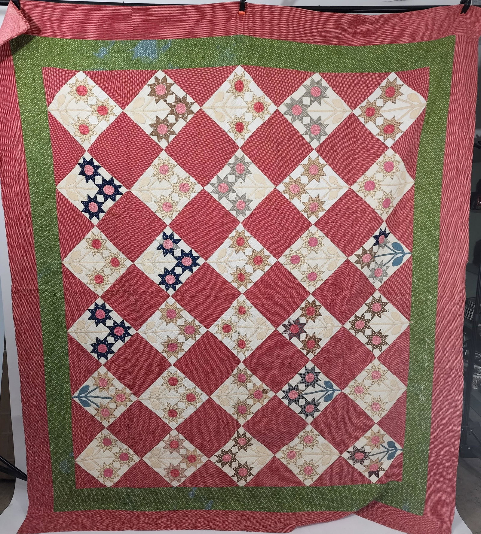 AMERICAN PIECED QUILT: Attributed to St. Clair County, Illinois, late 19th-early 20th century. Triple Sunflower appliquÃ© quilt. Flowers in navy and brown printed cotton. Alternating blocks are a small geometric printed r