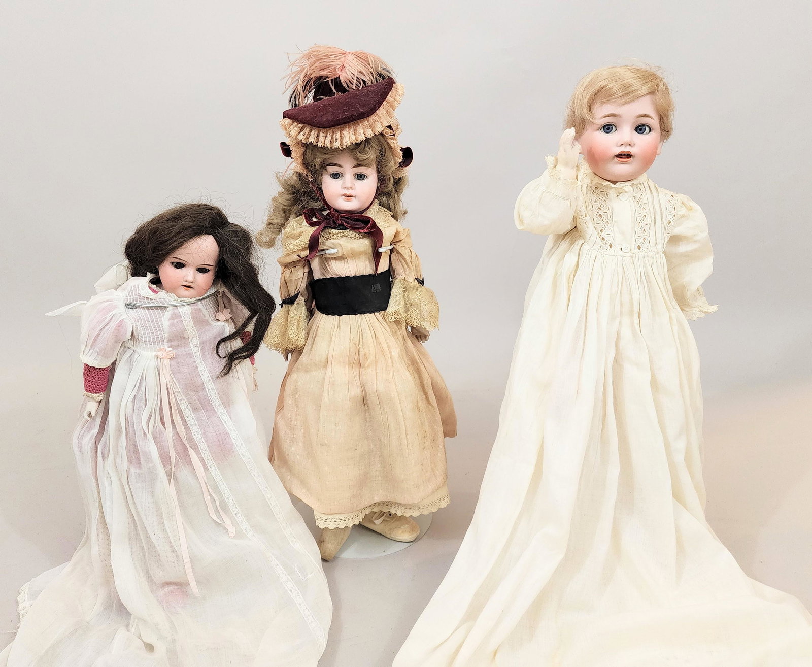 THREE BISQUE-HEAD DOLLS: All German. Includes an 18" doll with a moving tongue and composition body, marked "JDK", a unmarked 19" doll with later clothing and bisque hands, and a 22" doll marked "Alma" with bisque hands and i
