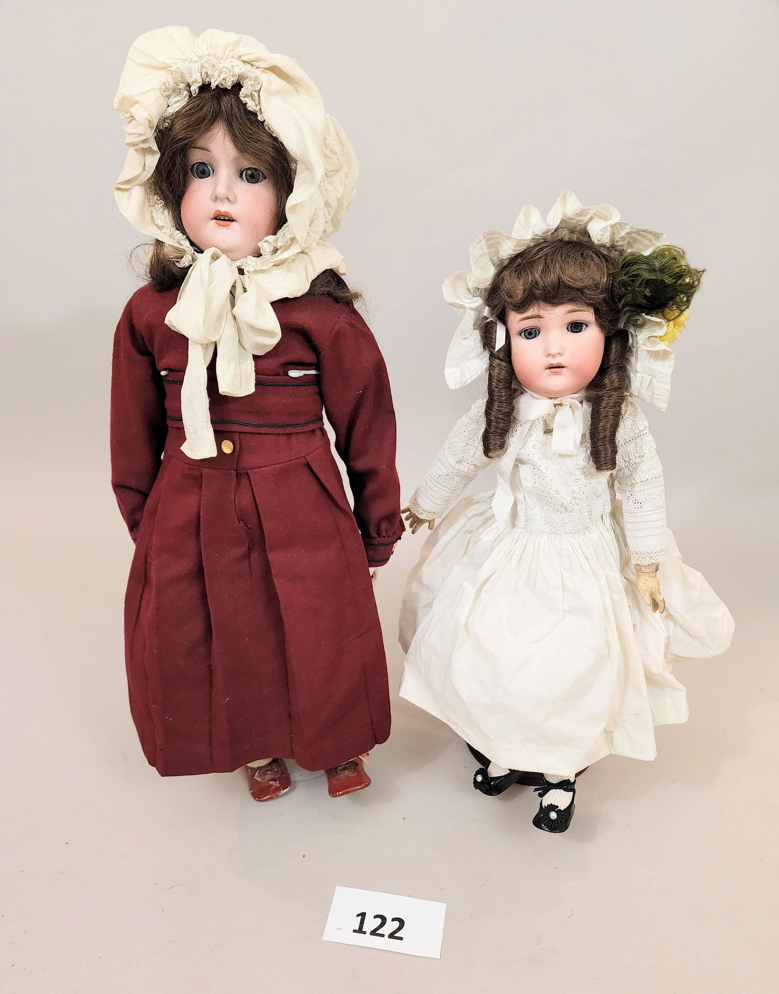 TWO BISQUE-HEAD DOLLS: Includes an Armand Marseille with bisque hands and a dark red dress, 29" high; and a German doll marked "AW W" with composition body and a white dress, 22" high.