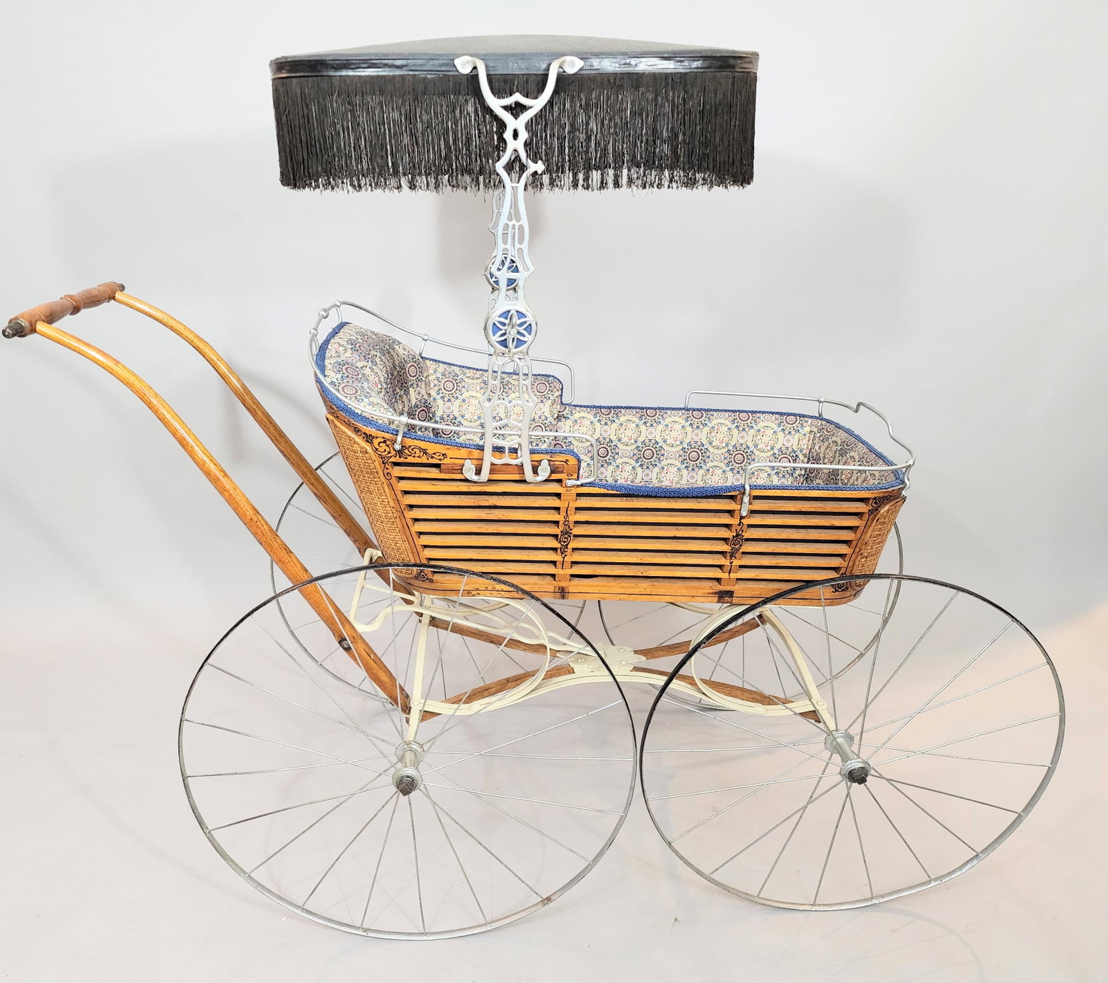 VICTORIAN BABY CARRIAGE: Wood slat design with woven corners and original black detailing. Original surrey top. 49" long.