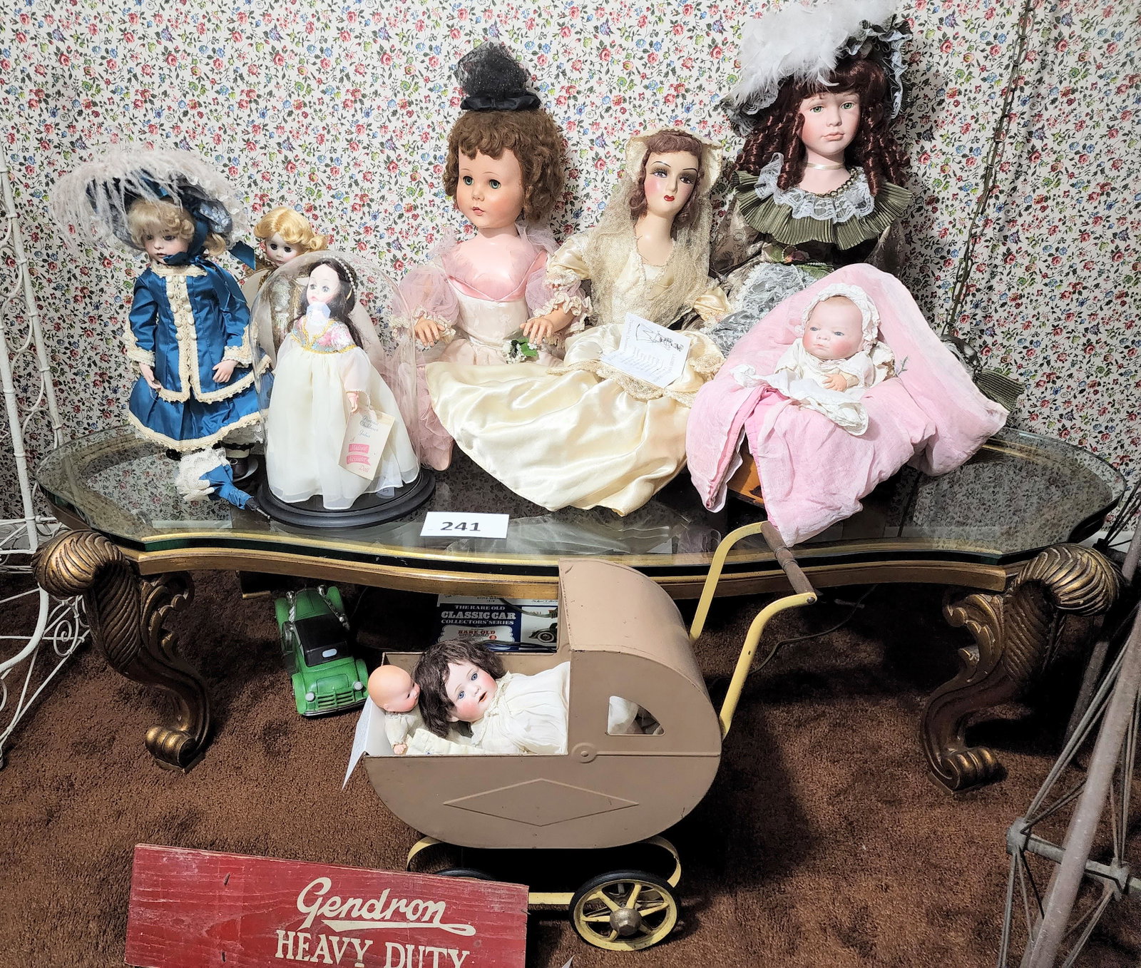 COLLECTION OF DOLLS: Includes a Hamilton Bru reproduction, a boudoir doll, a 7" German bisque-head, a 12" Nippon, other dolls, a painted metal doll carriage, and a Gendron carriage signboard.