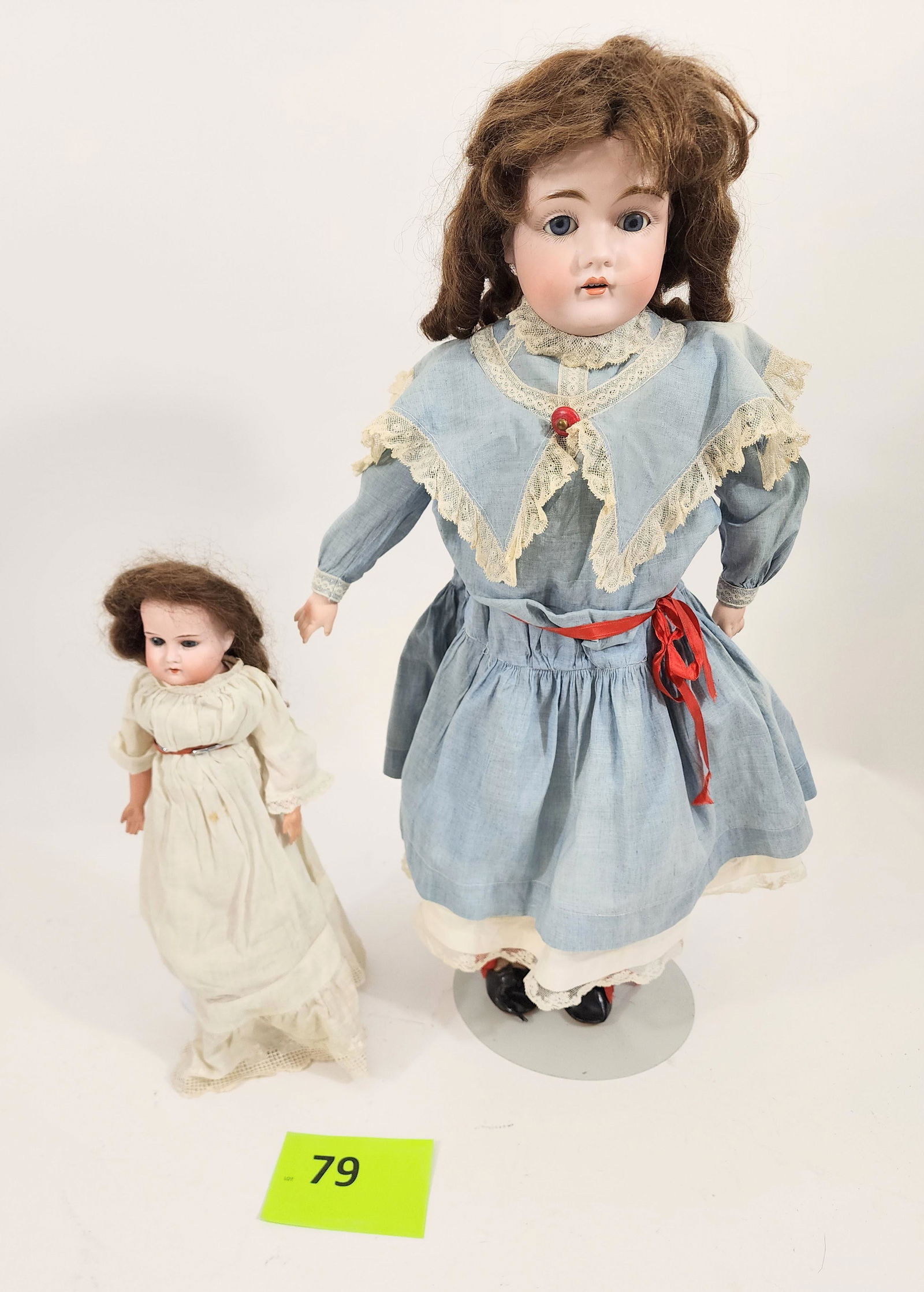 TWO BISQUE-HEAD DOLLS: One marked for Kestner, with bisque head and leather body, china hands, open mouth with teeth, chestnut curls. Appears to be in period dress and leather shoes. Smaller also with leather body and brown