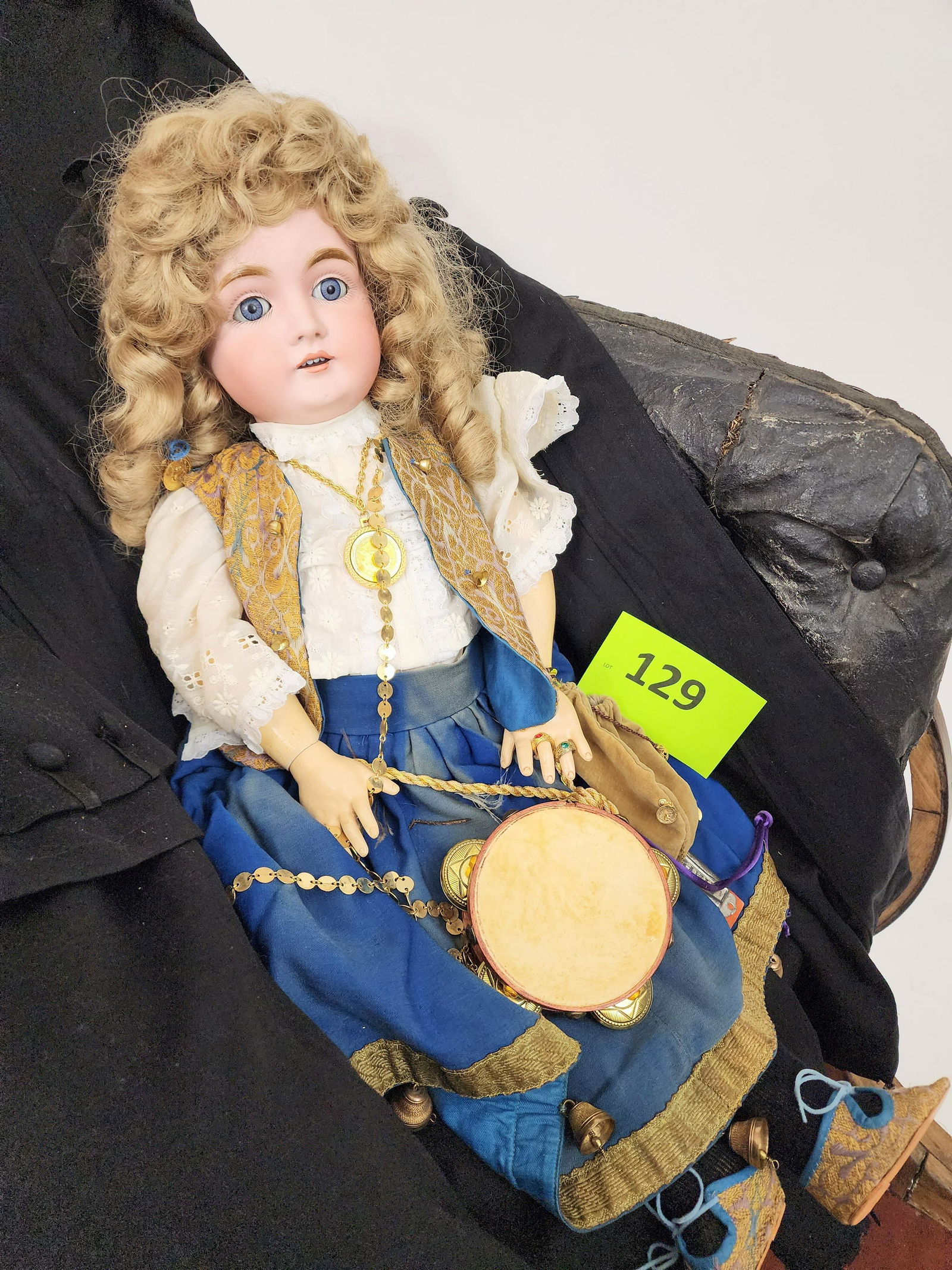 27" KESTNER SLEEPY-EYE DOLL: Bisque head and composition body, sleepy eyes, open mouth with teeth, blonde curls, elaborate stylized ethnic costume with blue skirt trimmed with bells, embroidered vest, gold-colored jewelry, tambou