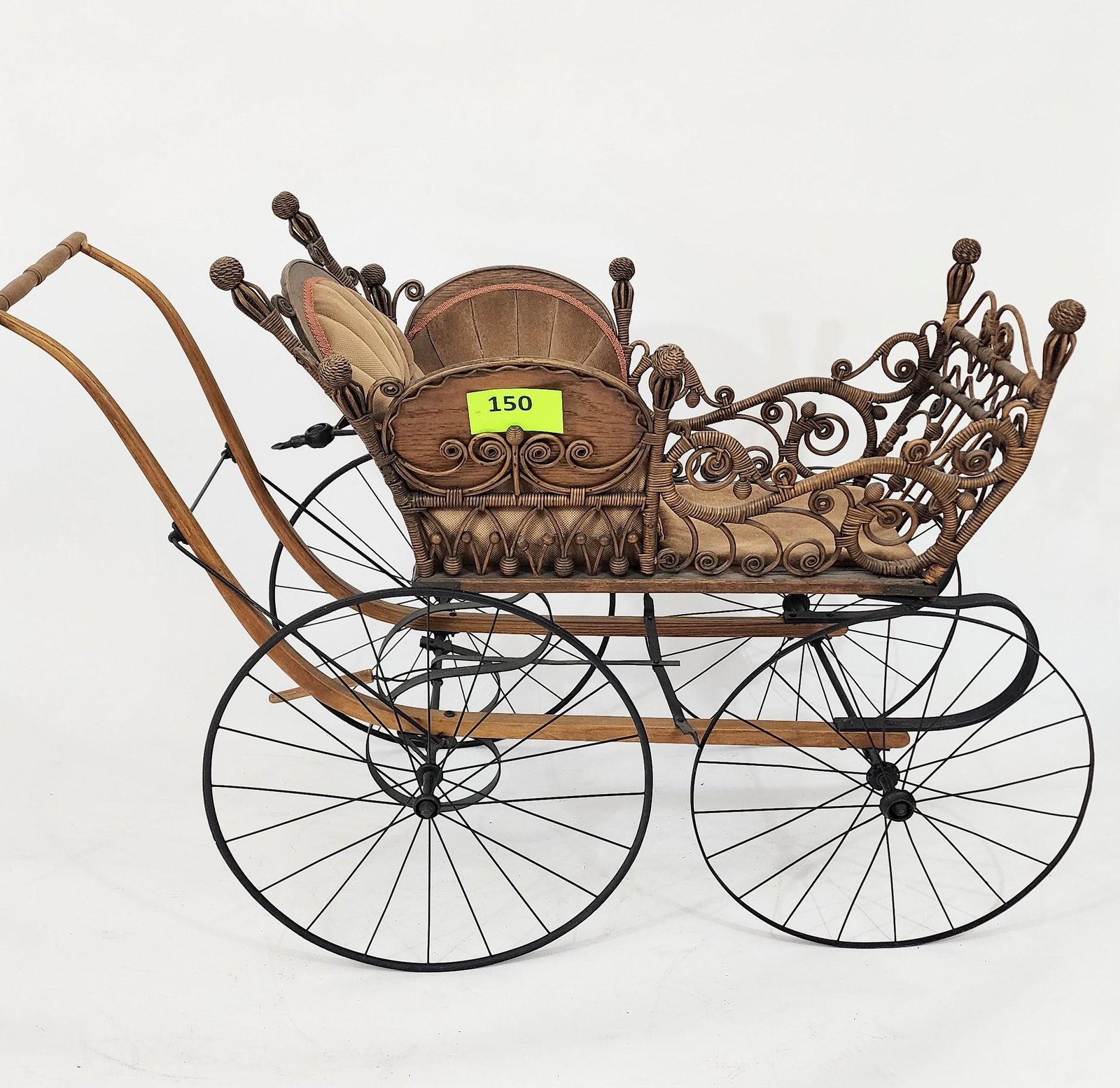 VICTORIAN RATTAN BABY CARRIAGE: Rattan-work carriage with curlicues and stick-and-ball decoration. Vintage upholstery. 55" long.