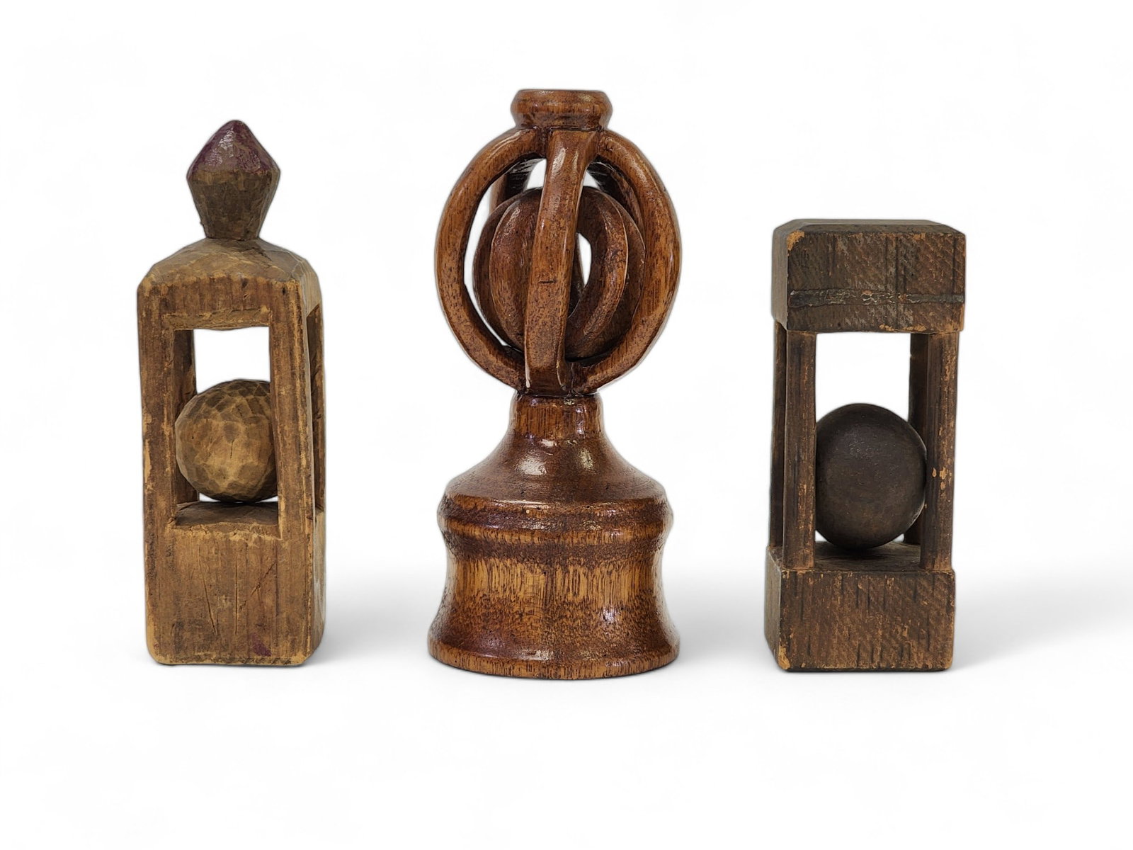 THREE FOLK ART WHIMSIES: American, late 19th-early 20th century. Two caged balls and a concentric sphere on turned base. The last is inscribed on the underside "To Esther from Phil 12-28-15" and is 6" high.
