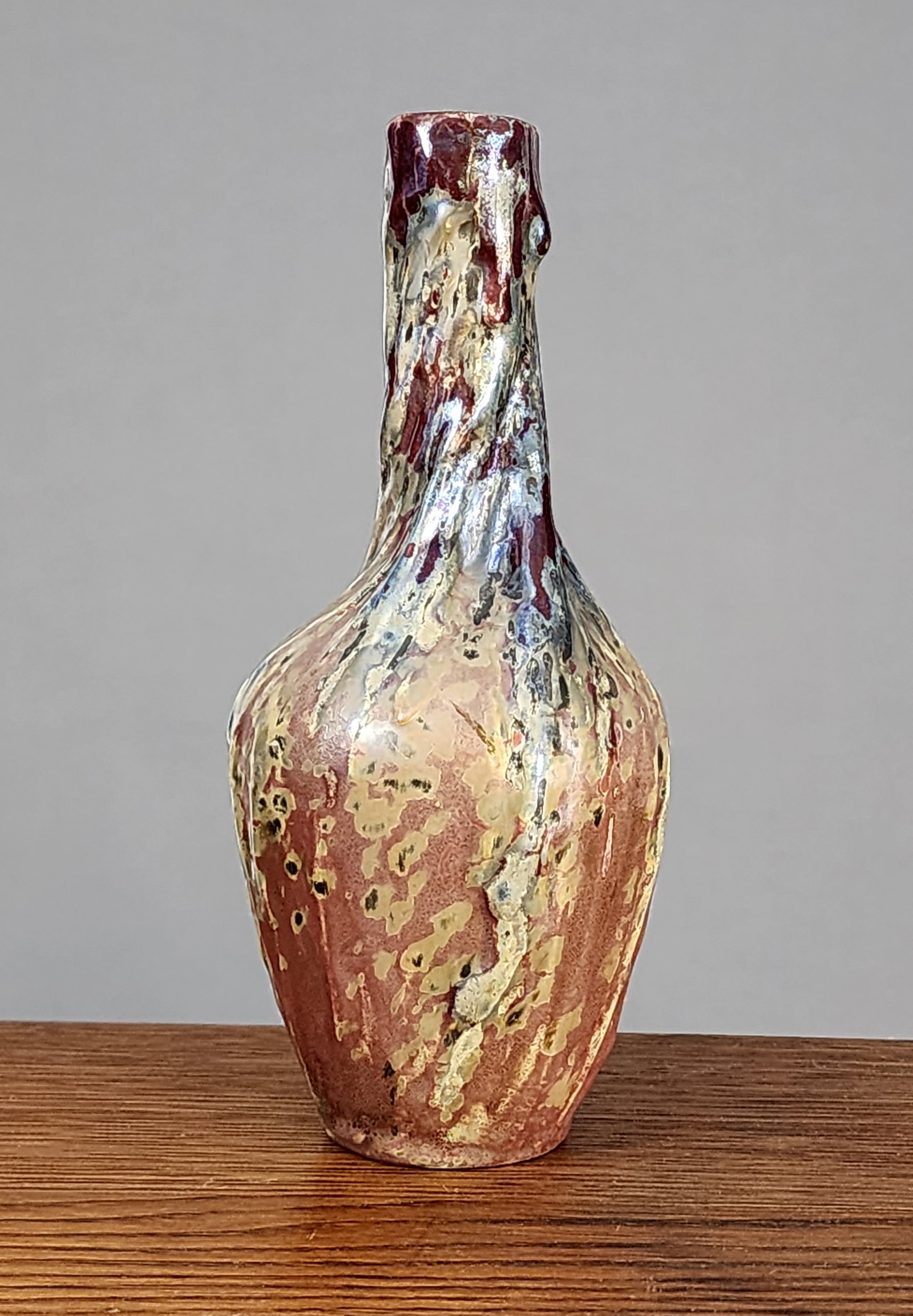 KELLER & GUERIN LUNEVILLE POTTERY VASE: France, 1st half 20th century. Ovoid base with a long twisted cylindrical ribbed neck. Iridescent glaze in red, gold, black and salmon pink. Marked on the base. 7"h.