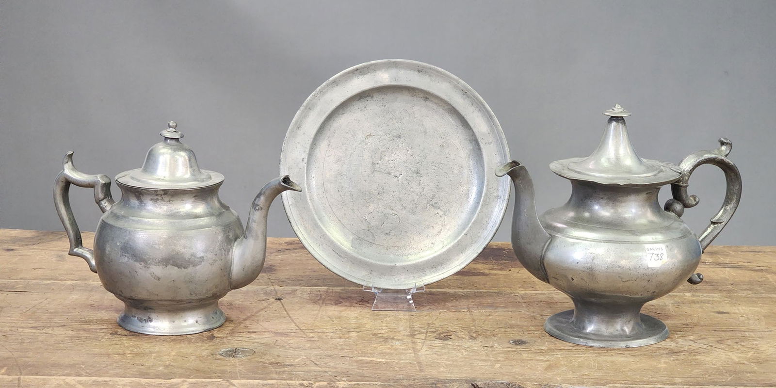 THREE PIECES OF PEWTER: American, 19th century. Includes two teapots and a plate, all unmarked. Tallest pot is 8" high.