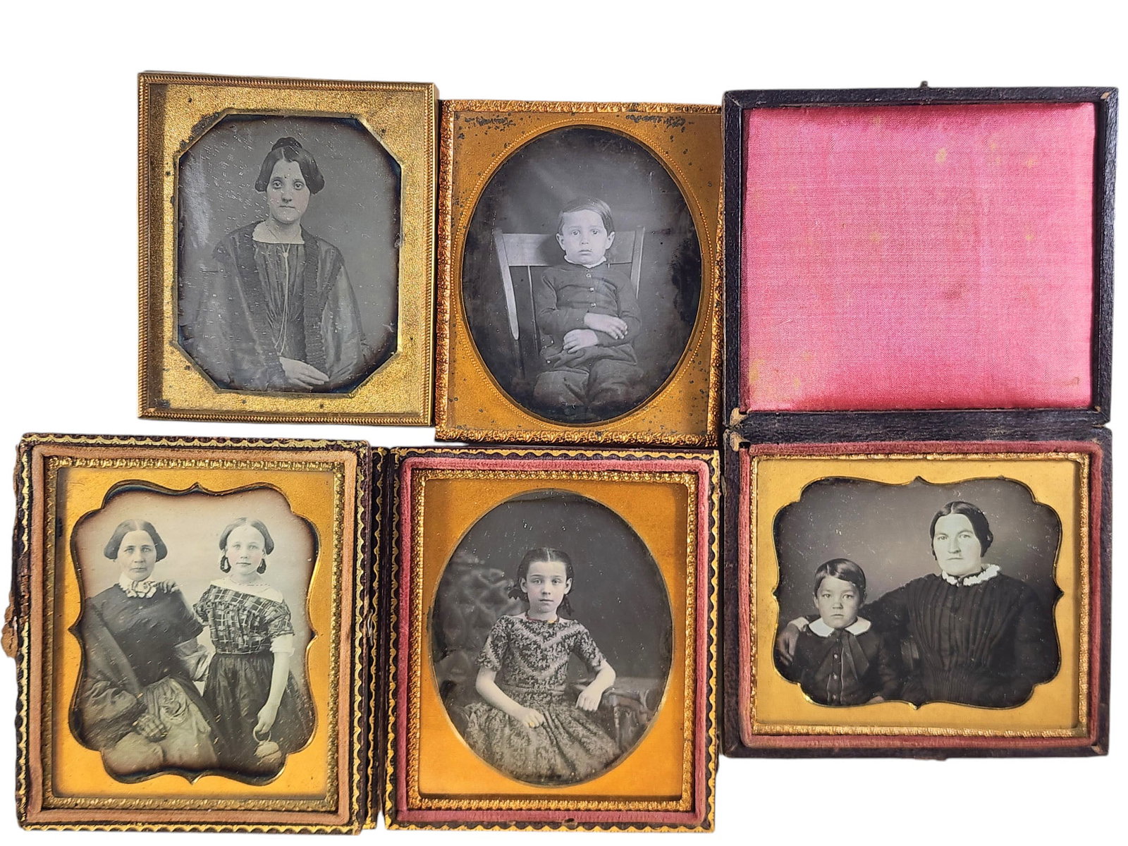 FIVE SIXTH PLATE DAGUERREOTYPES: Mid-19th century. A portrait of a young girl in a striking dress, one of a boy in a windsor chair, two with mothers and their children, and one of a woman. Three are in pressed leather cases.