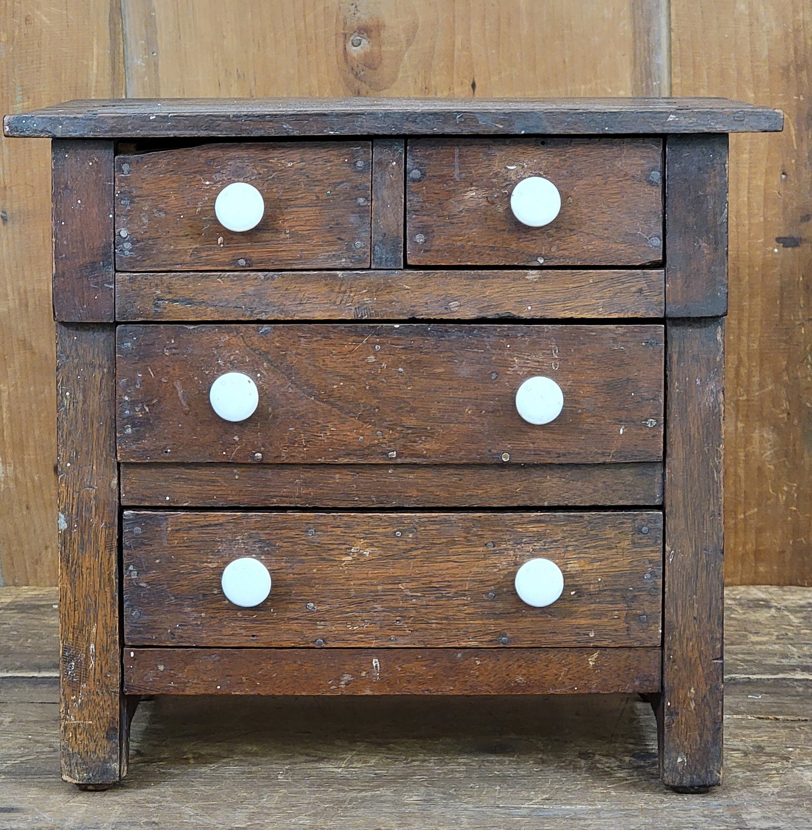 MINIATURE CHEST OF DRAWERS: American, 19th century, walnut and various secondary woods (including basswood, cedar, and mahogany from cigar boxes). Two over two drawers, and retaining its original finish and pulls. 10.75" high, 1