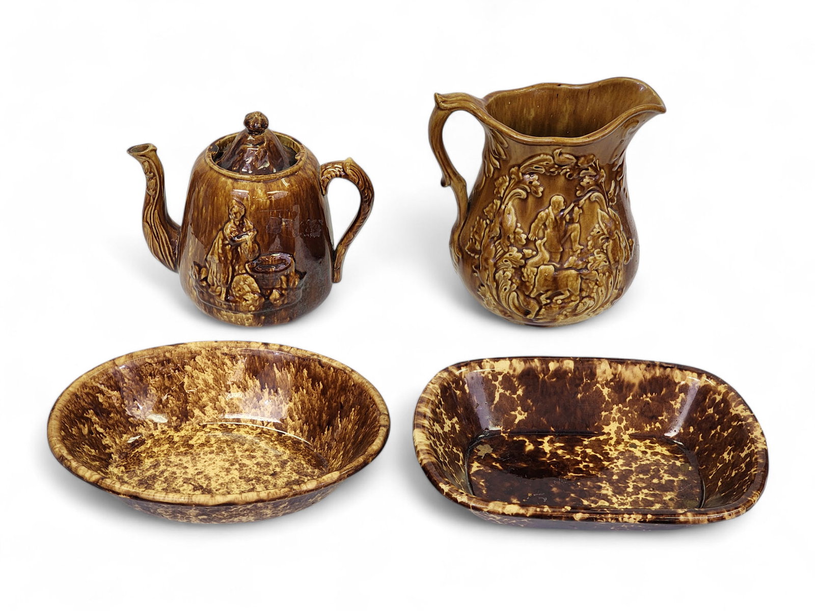FOUR PIECES OF ROCKINGHAM: American, 19th century. Includes two open dishes, a pitcher with hunt scene, and a Rebecca at the Well teapot. Pitcher is 9" high. Provenance: From an Idaho Collection