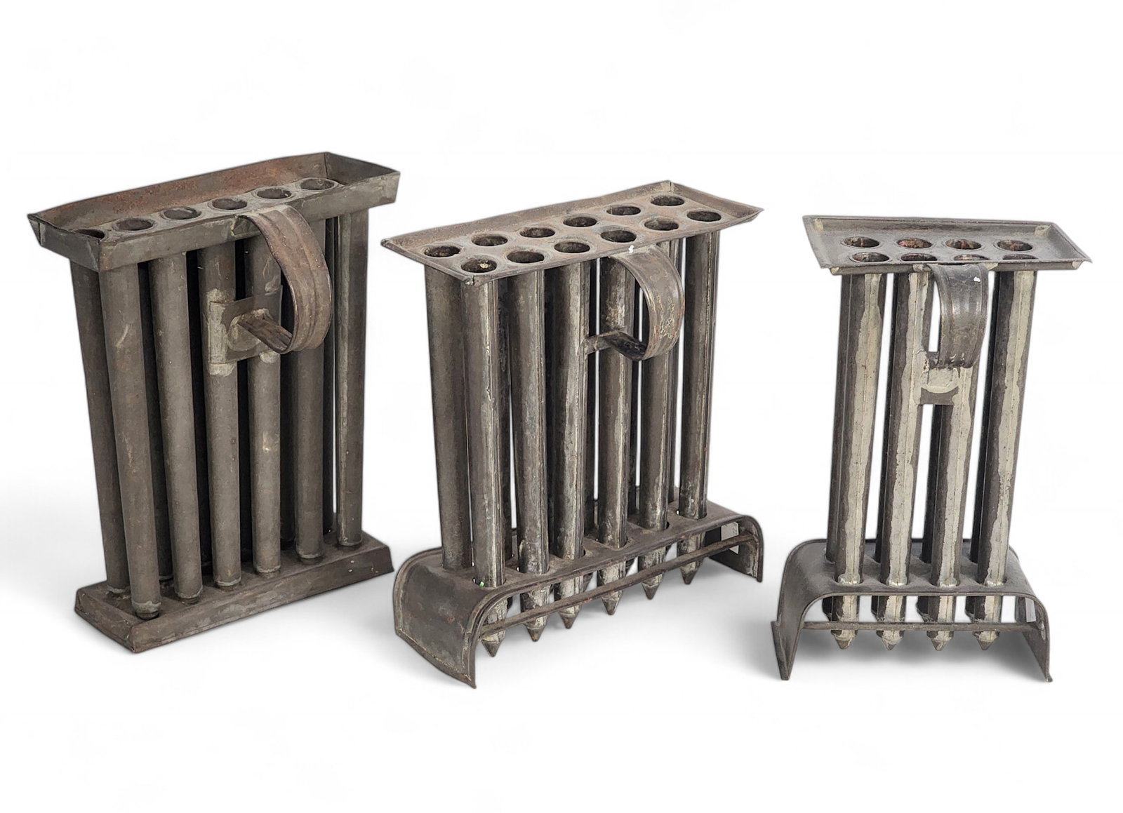 THREE TIN CANDLE MOLDS: American, 19th century. Includes two 12-tube molds and one eight-tube mold. Largest is 10.5" long. Provenance: private collection.