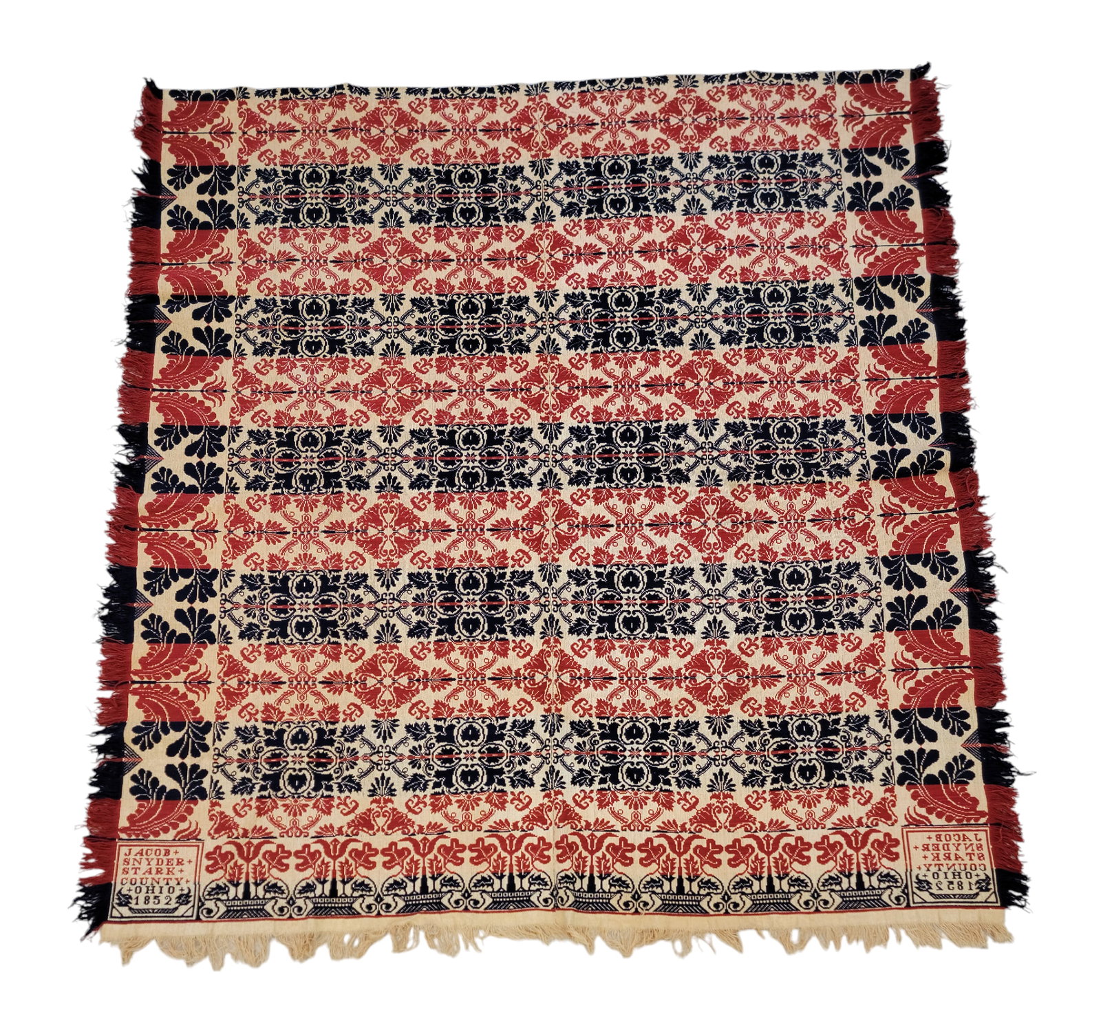 STARK COUNTY, OHIO COVERLET: Stark County, Ohio, 1852. A two-piece coverlet woven in red and blue, wide tulip borders on longer sides, tulip baskets on foot border, centerfield with medallion designs, corner blocks signed "JACOB