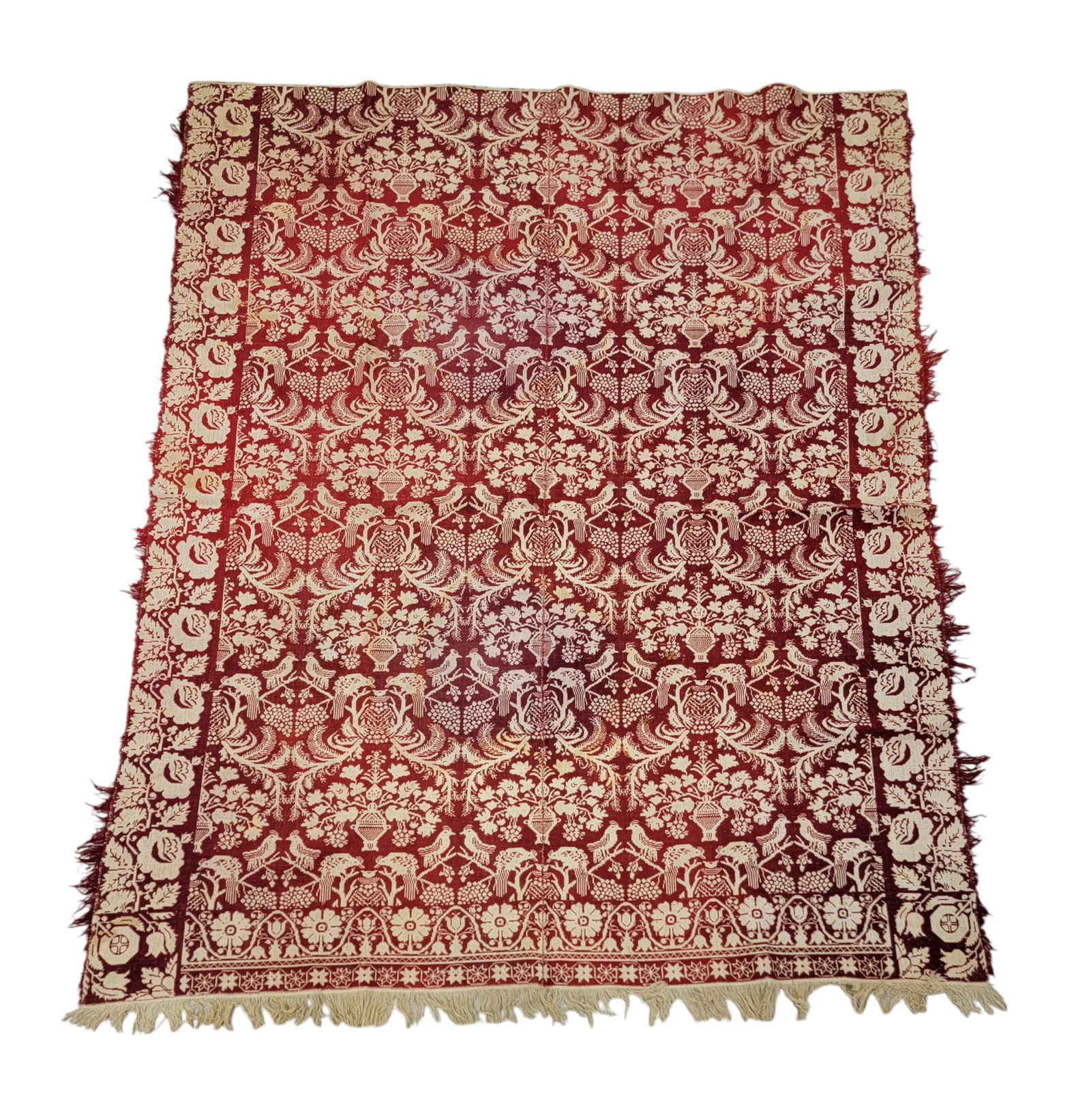JACQUARD COVERLET: American, mid-19th century. A two-piece coverlet woven in red and white, rose borders on the longer sides, tulip and flower foot border, centerfield of peacocks feeding their young and urns of flowers