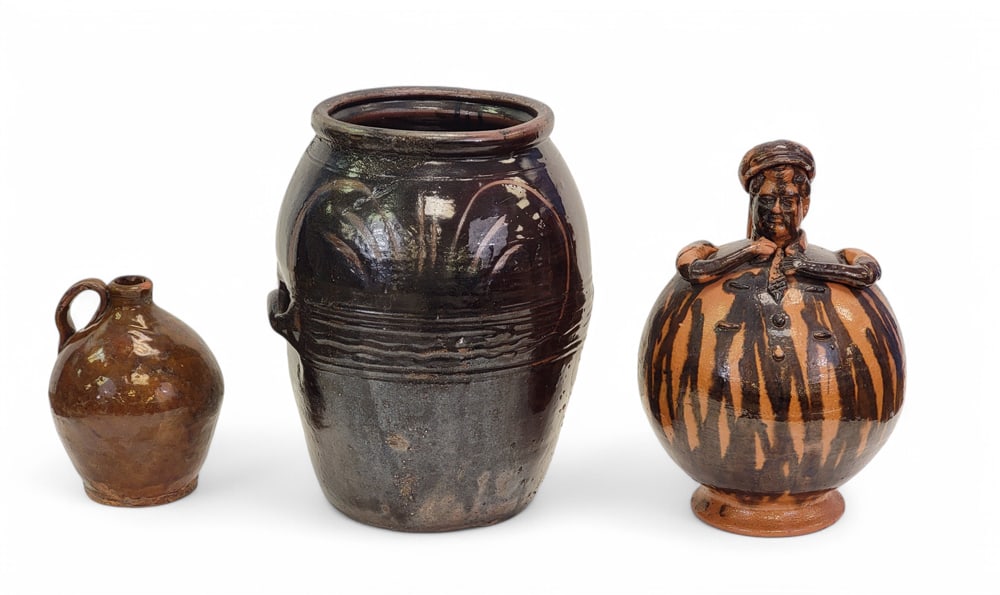 THREE PIECES OF REDWARE: 19th-20th century. Includes a large, probaby Chinese, jar with handles, a small jug, and an illegibly signed Mexican Pulque jug in the form of a man wearing a tie, and with a cap. The last is 11" high