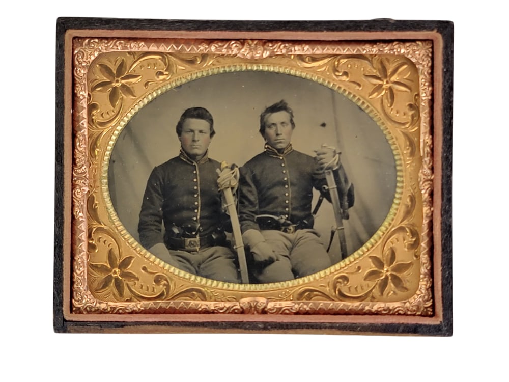 QUARTER PLATE TINTYPE OF ARMED CIVIL WAR SOLDIERS: Seated double portrait, each uniformed soldier holding his sword (likely M1860 cavalry sabers) and with a revolver tucked in his belt, in a pressed leather case. Provenance: Denker Collection, Delawar