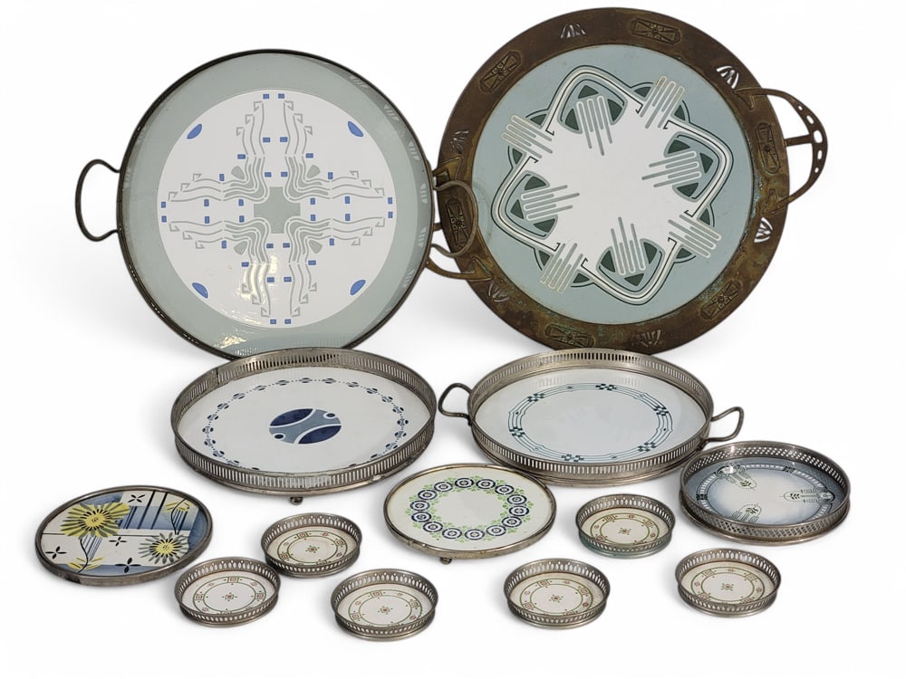 COLLECTION OF ART DECO TRAYS, TRIVETS, AND COASTERS: Mostly German, 1920-1940. All with metal frames and decorated porcelain inserts. Includes 4 trays, three trivets, and a set of 6 matching coasters. Largest tray is 14.5" diameter (not including handle