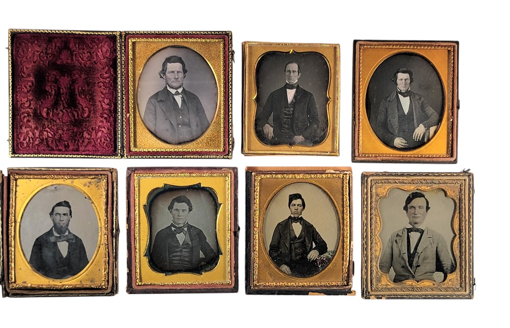 SEVEN SIXTH PLATE PHOTOGRAPHS OF GENTLEMEN: Includes four daguerreotypes and three ambrotypes. One ambro is dated November 1857 in the plate, and another depicts a tinted jacquard woven table cover and has a brass mat marked for J.W. Wykes. Pro