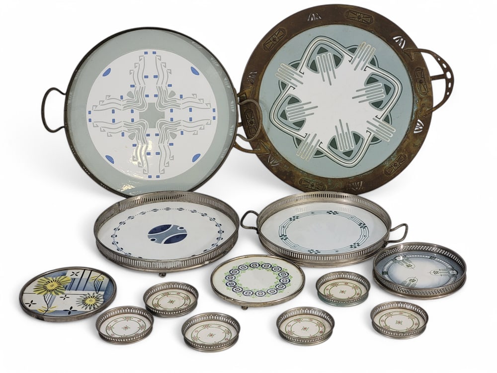 COLLECTION OF ART DECO TRAYS, TRIVETS, AND COASTERS: Mostly German, 1920-1940. All with metal frames and decorated porcelain inserts. Includes 4 trays, three trivets, and a set of 6 matching coasters. Largest tray is 14.5" diameter (not including handle